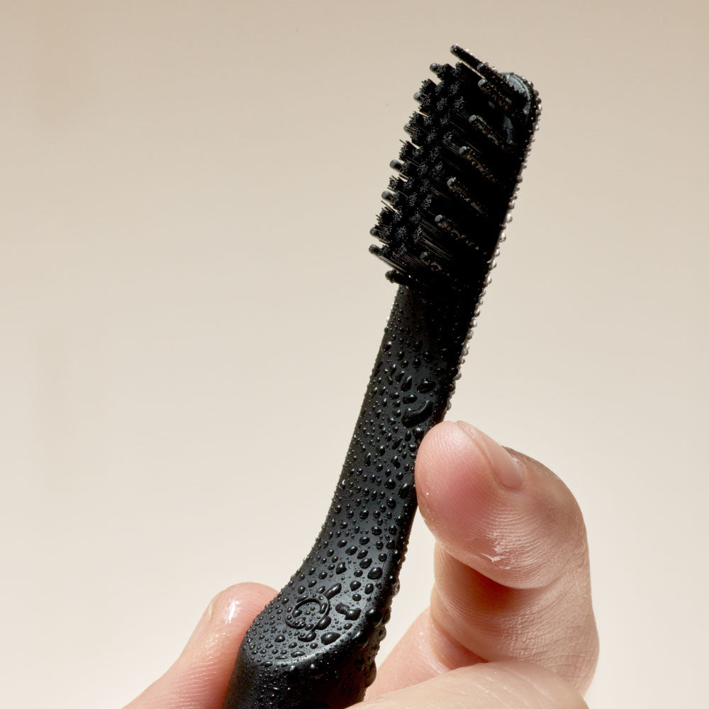 Black bristle brush held by a hand against a beige background