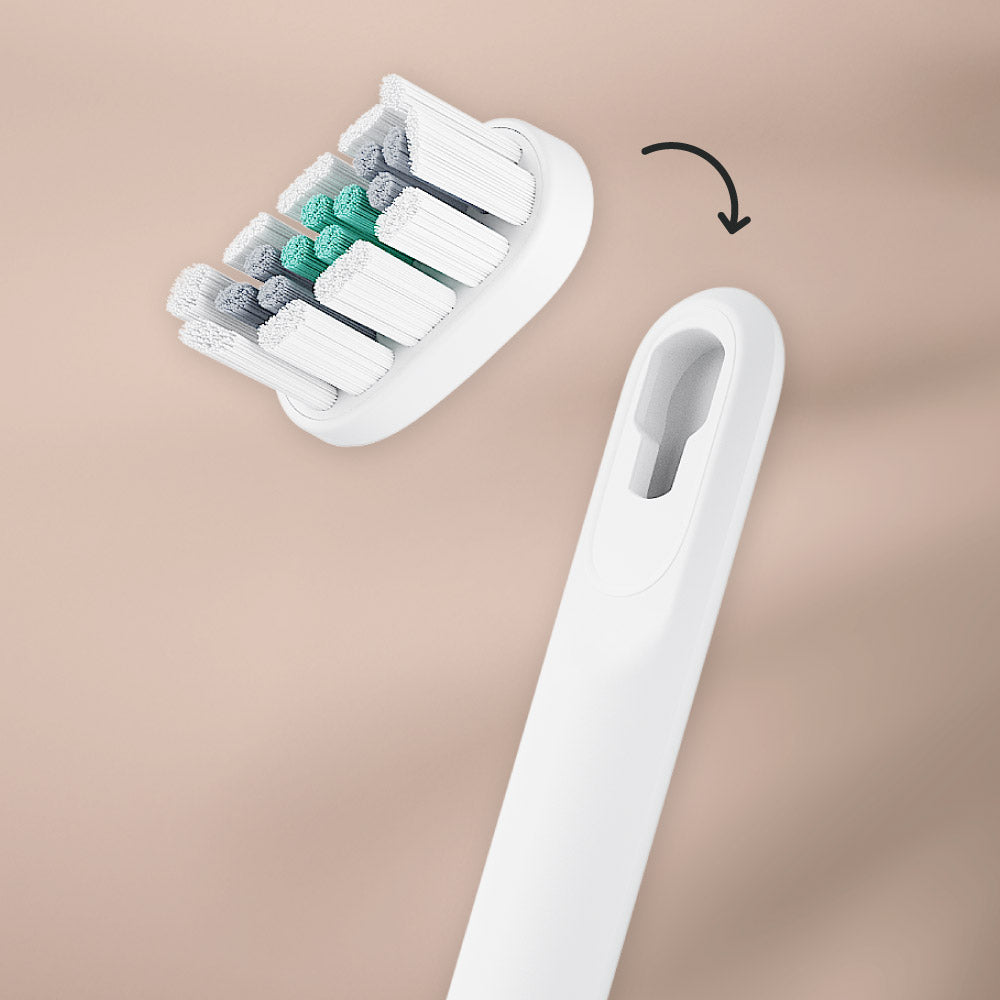 White electric toothbrush head with additional brush heads in a holder on a beige background