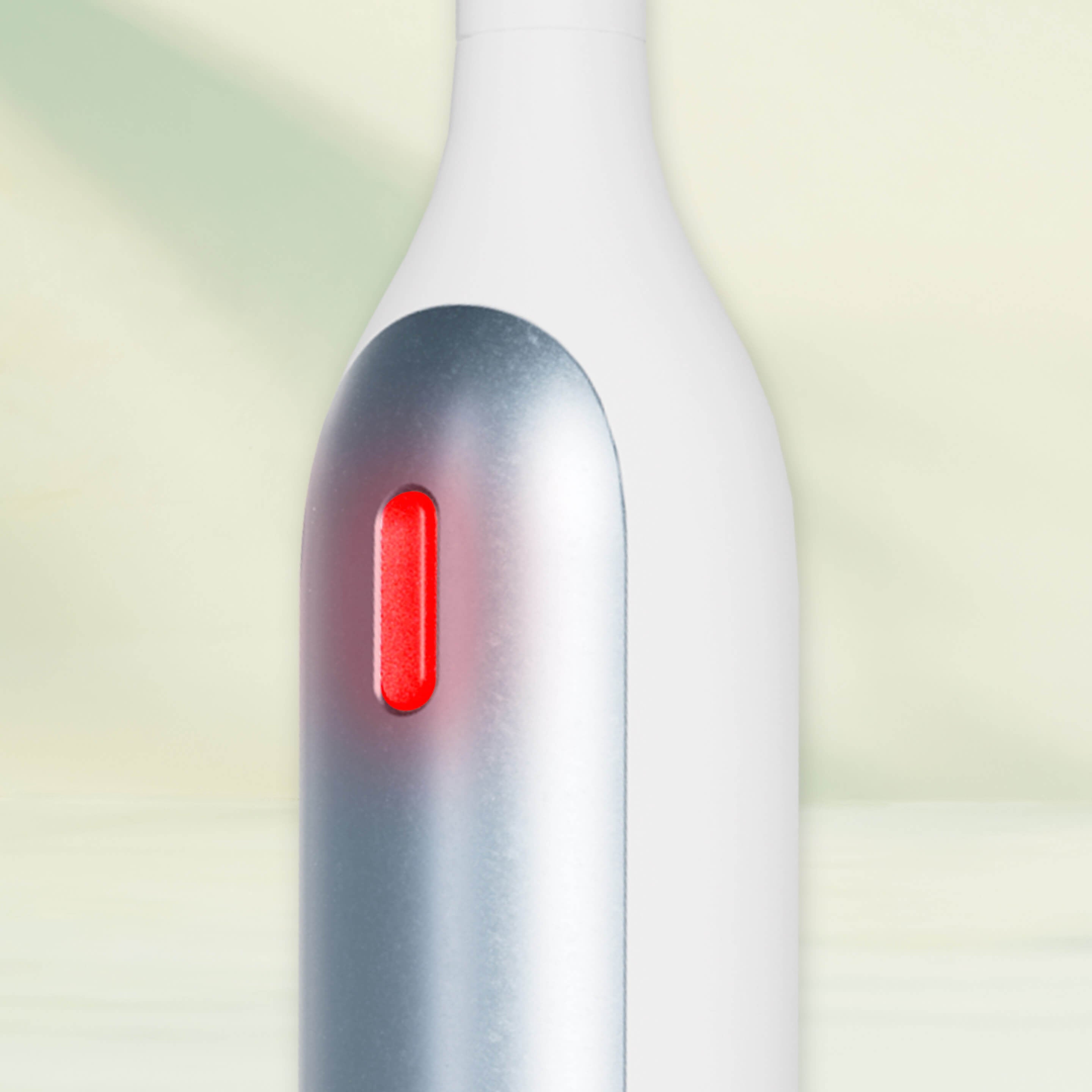 Close-up of the Rev toothbrush handle with a glowing red indicator light.