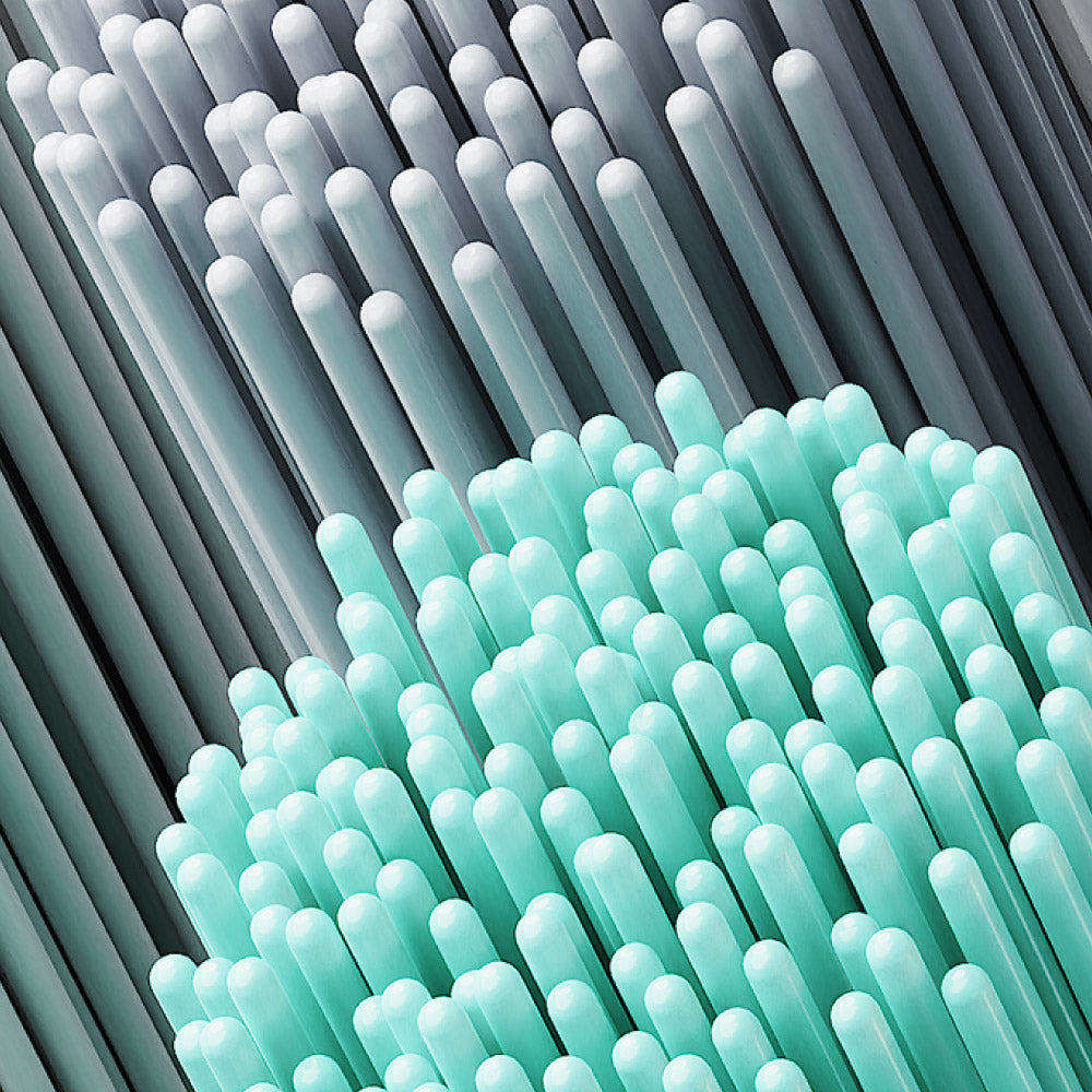 A close-up, abstract shot of electric toothbrush bristles. The top half shows grey and white bristles, while the bottom half features vibrant teal bristles.