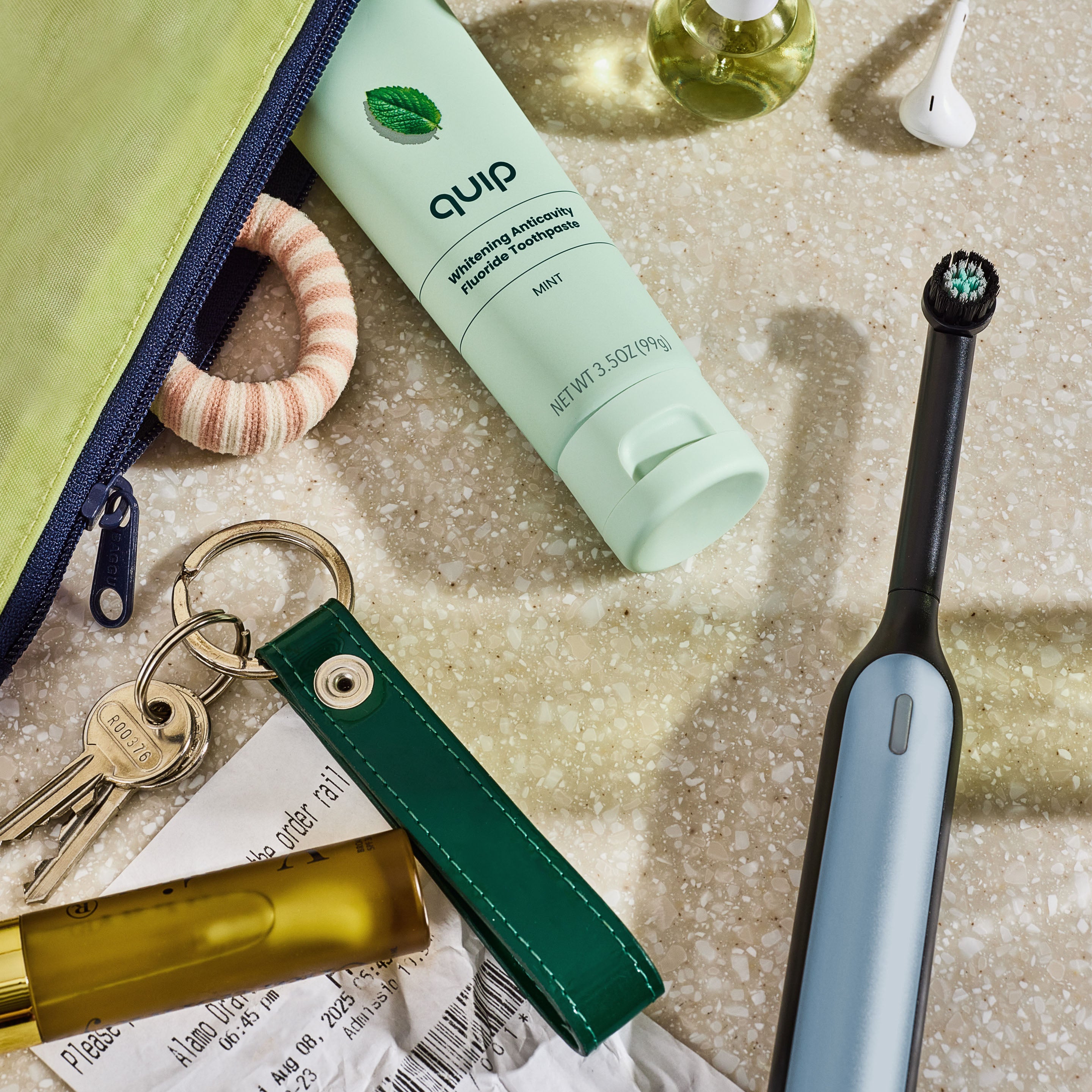 Quip electric toothbrush, keychain, and other items on a textured surface