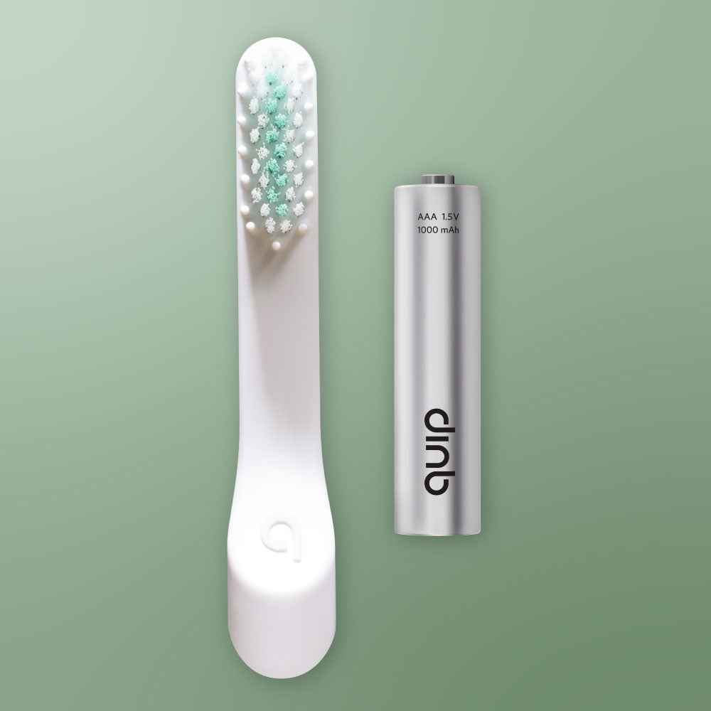 White electric toothbrush with green bristles and a silver battery pack on a light green background