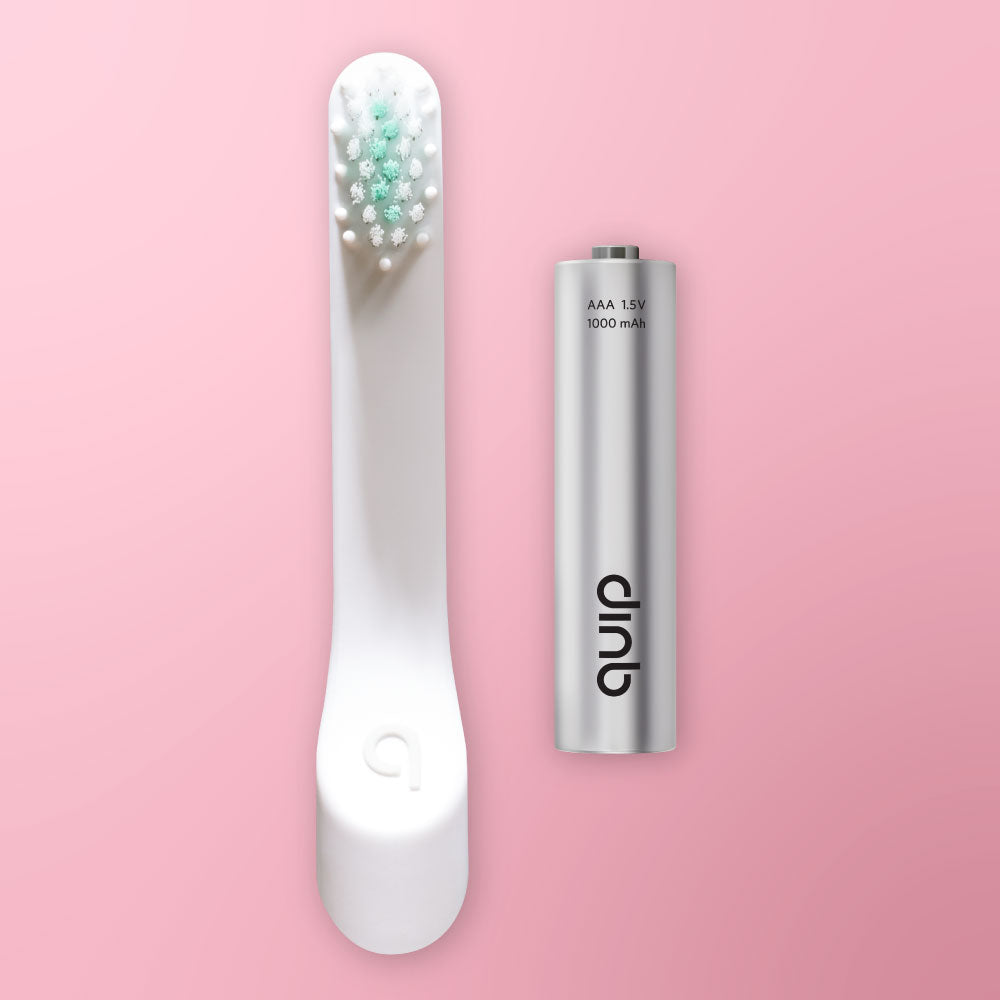 White electric toothbrush with visible bristles and a silver battery pack on a pink background