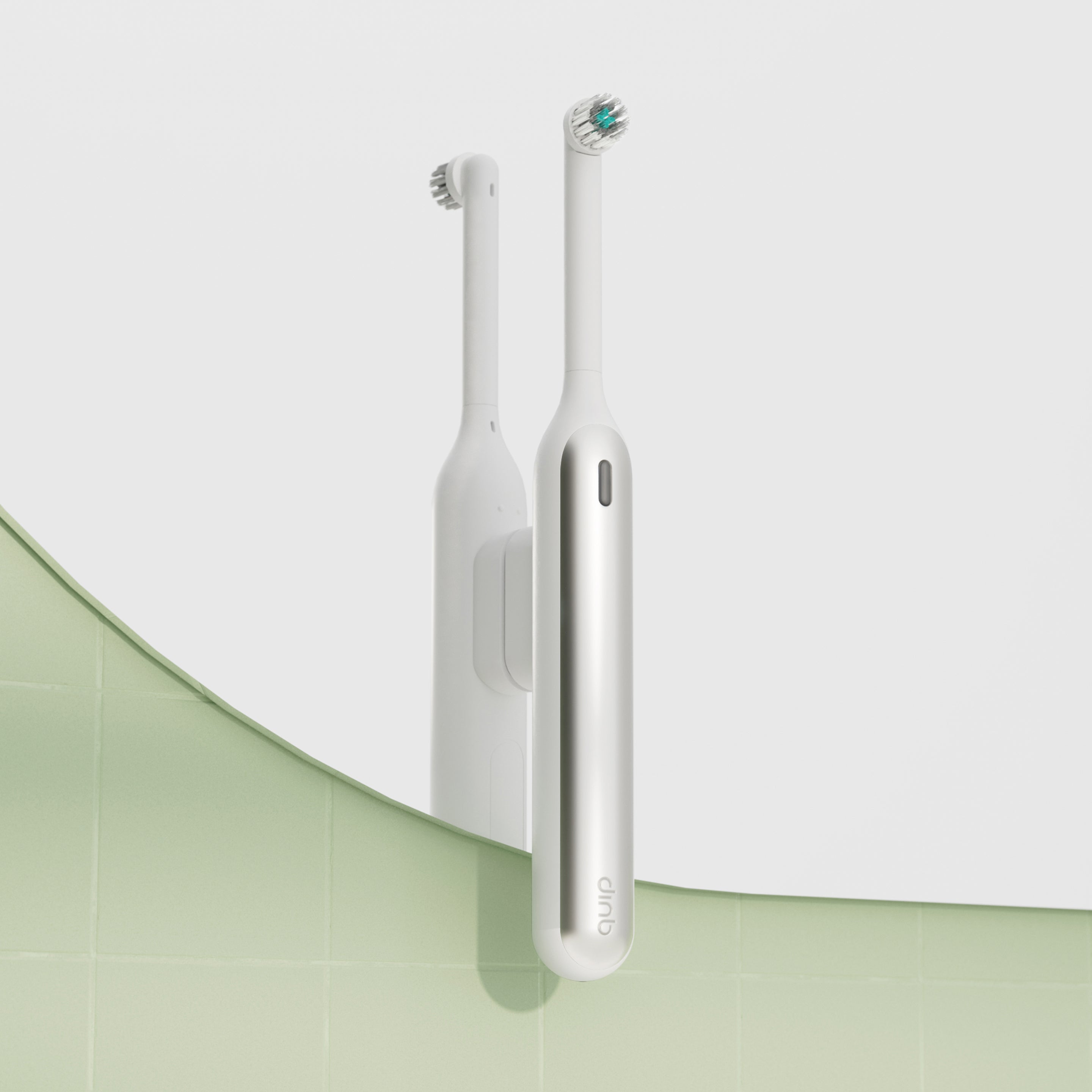 White electric toothbrush mounted vertically on a bathroom mirror using a white Rev mirror mount, with a soft green tiled wall reflected below.
