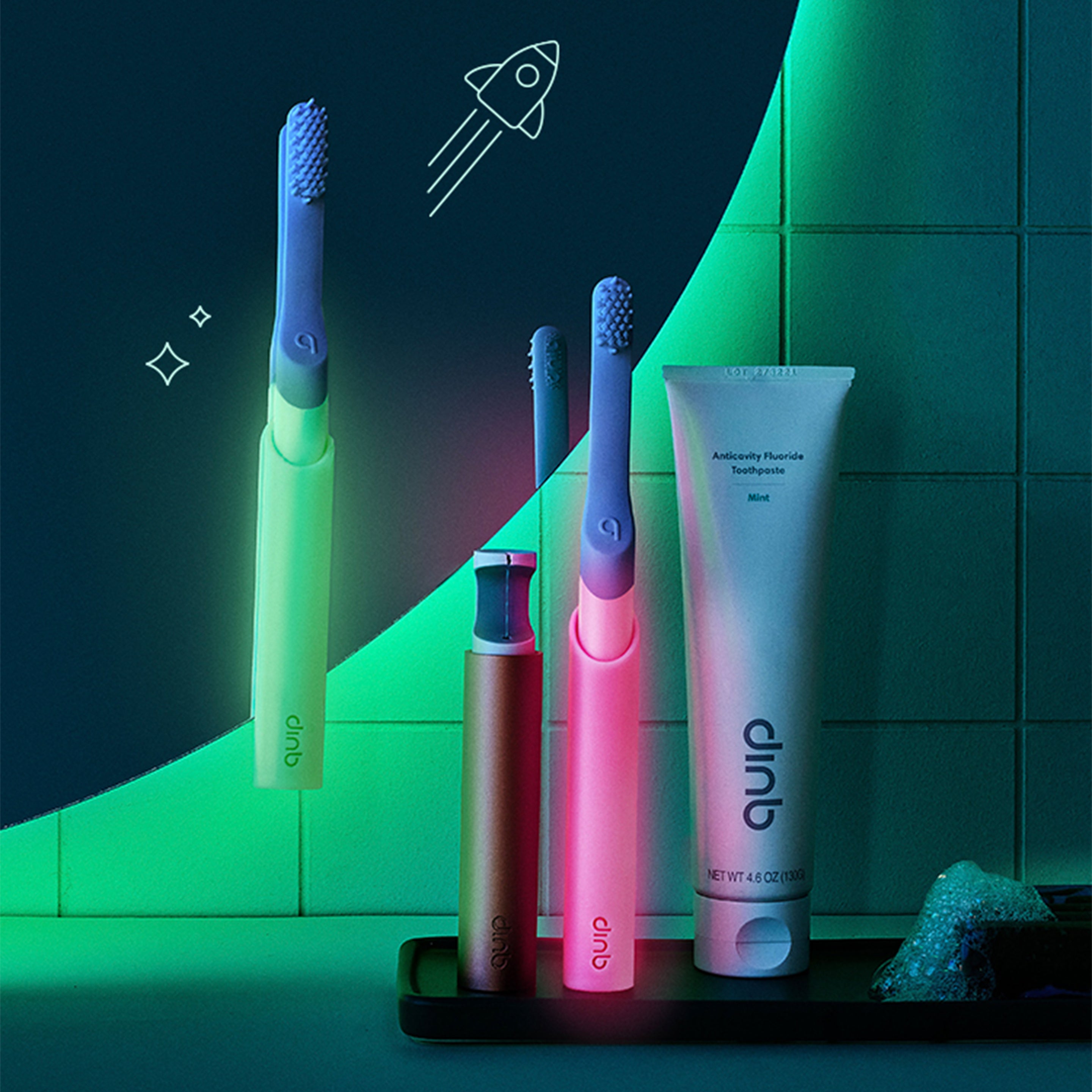 quip's glow in the dark adult toothbrushes in green and in pink on a bathroom counter, with the lights off and they are glowing.