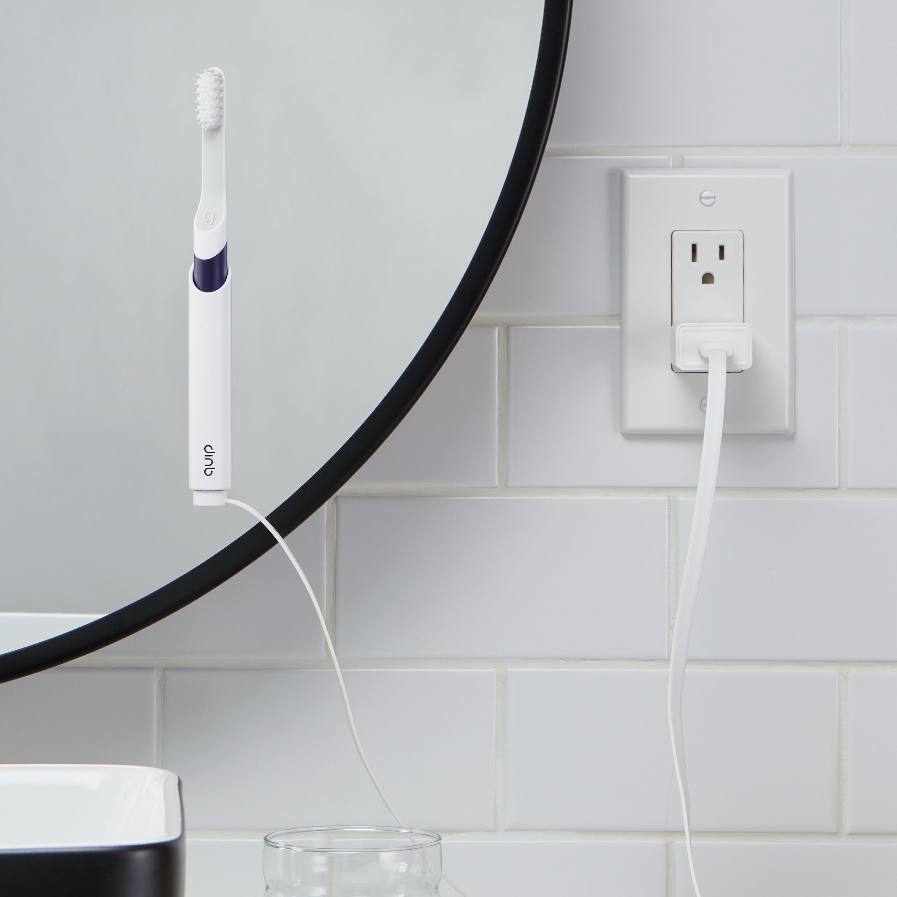 A rechargeable sonic toothbrush with a navy blue handle mounted on a mirror, and a white magnetic USB-A cable connecting together.