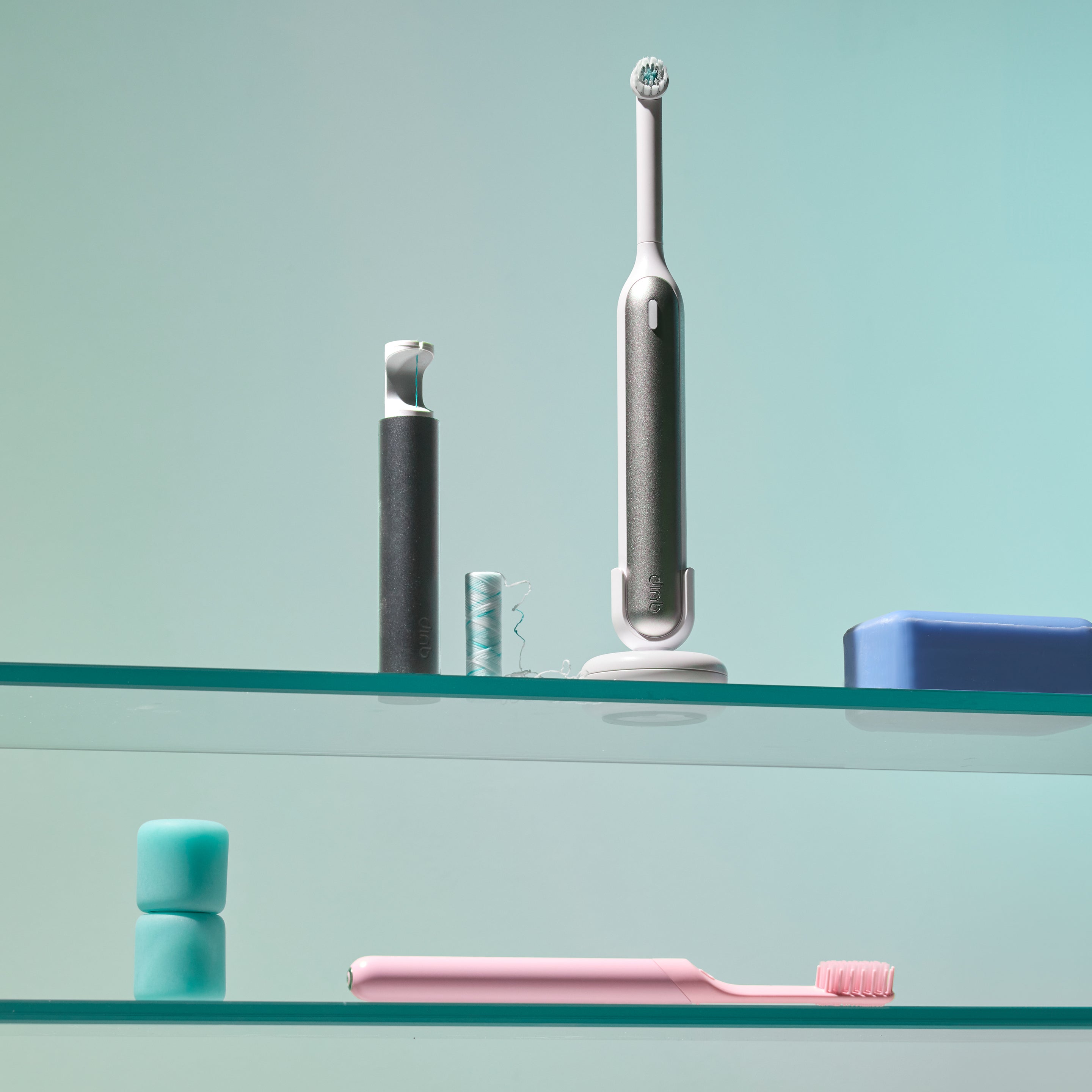 quip Rev oscillating toothbrush sits on a shelf with a quip floss string