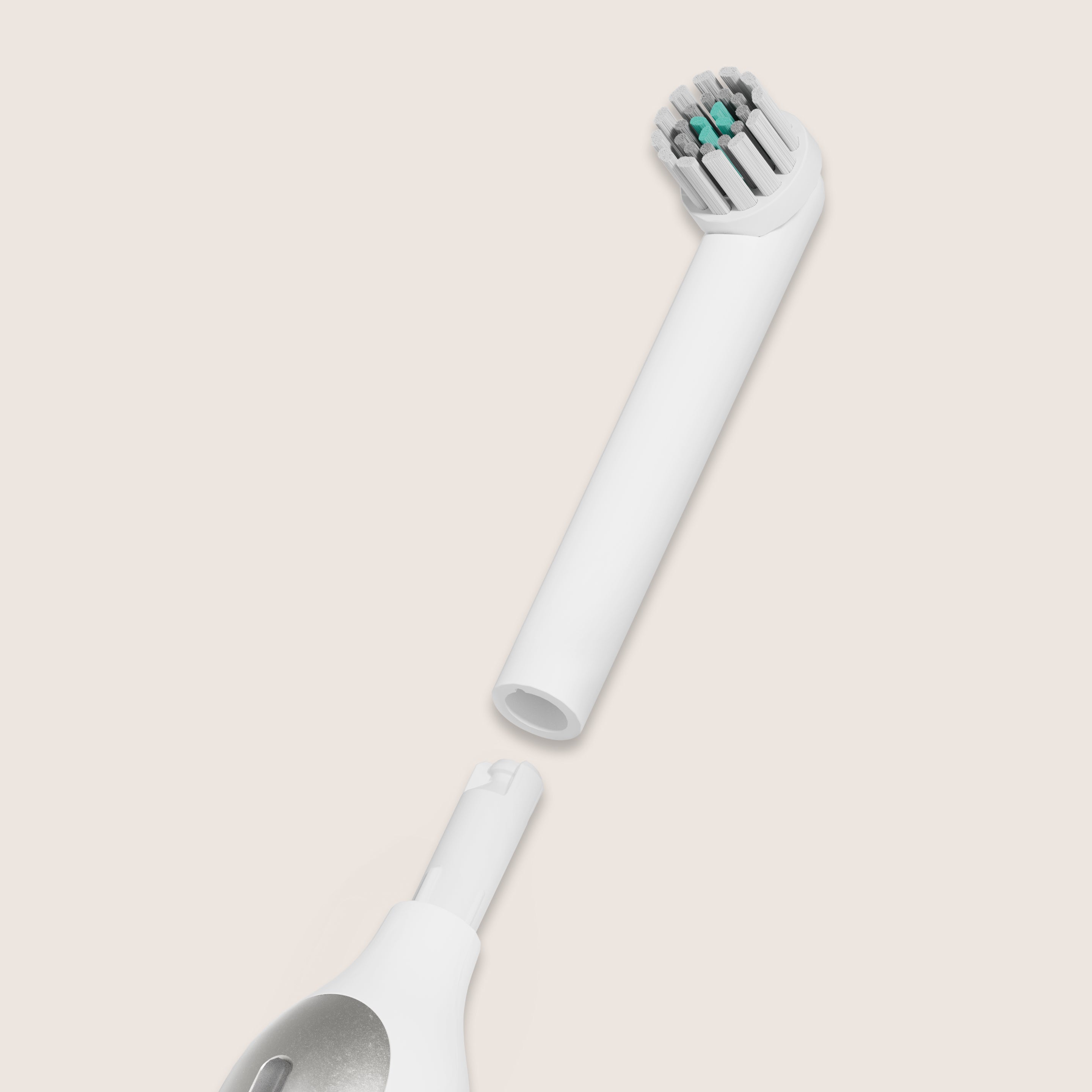 A white quip Rev brush head refill detached from the main body of a white and silver quip electric toothbrush, against a light peach background.