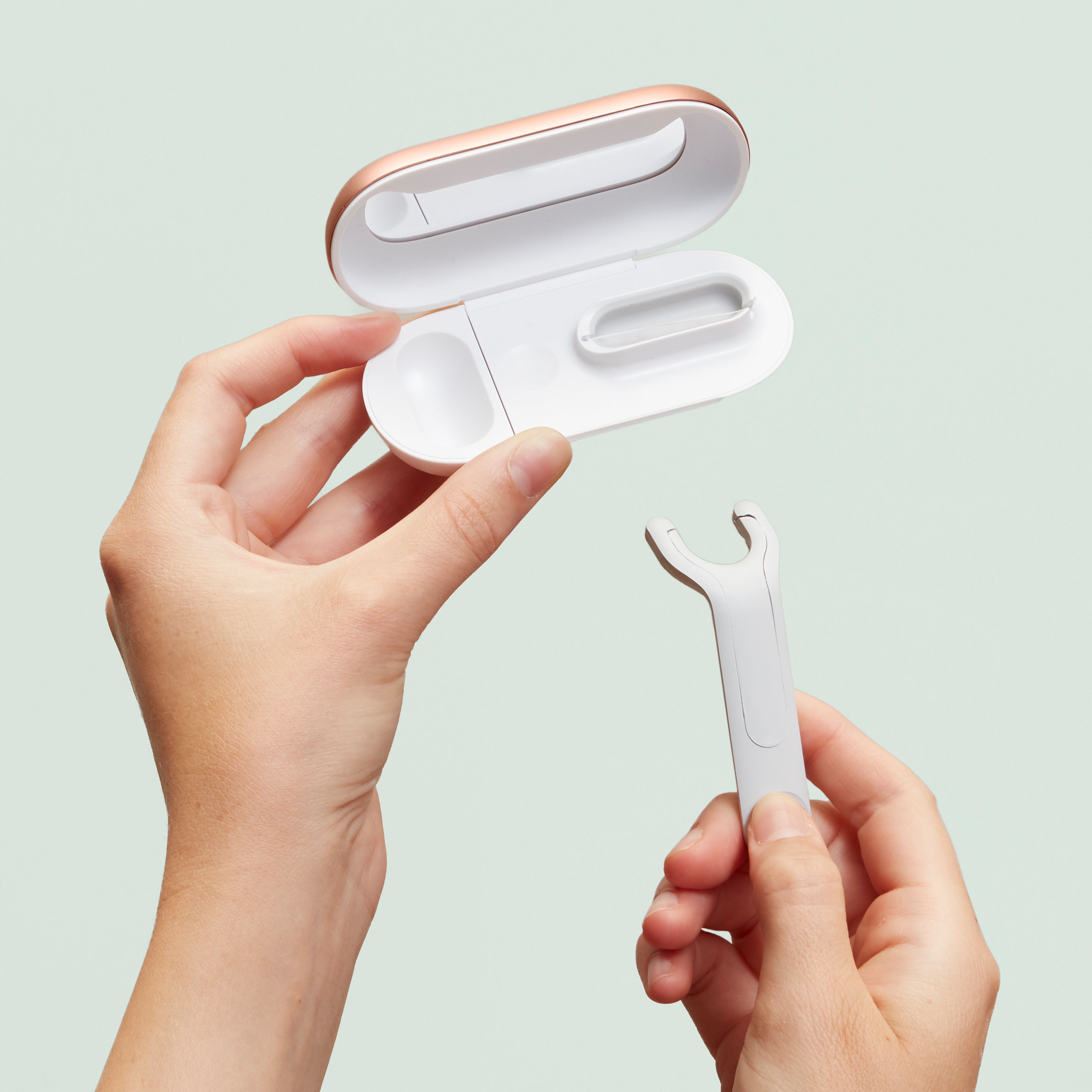 Hands holding an open white floss pick case with a refill pick being lifted toward it.