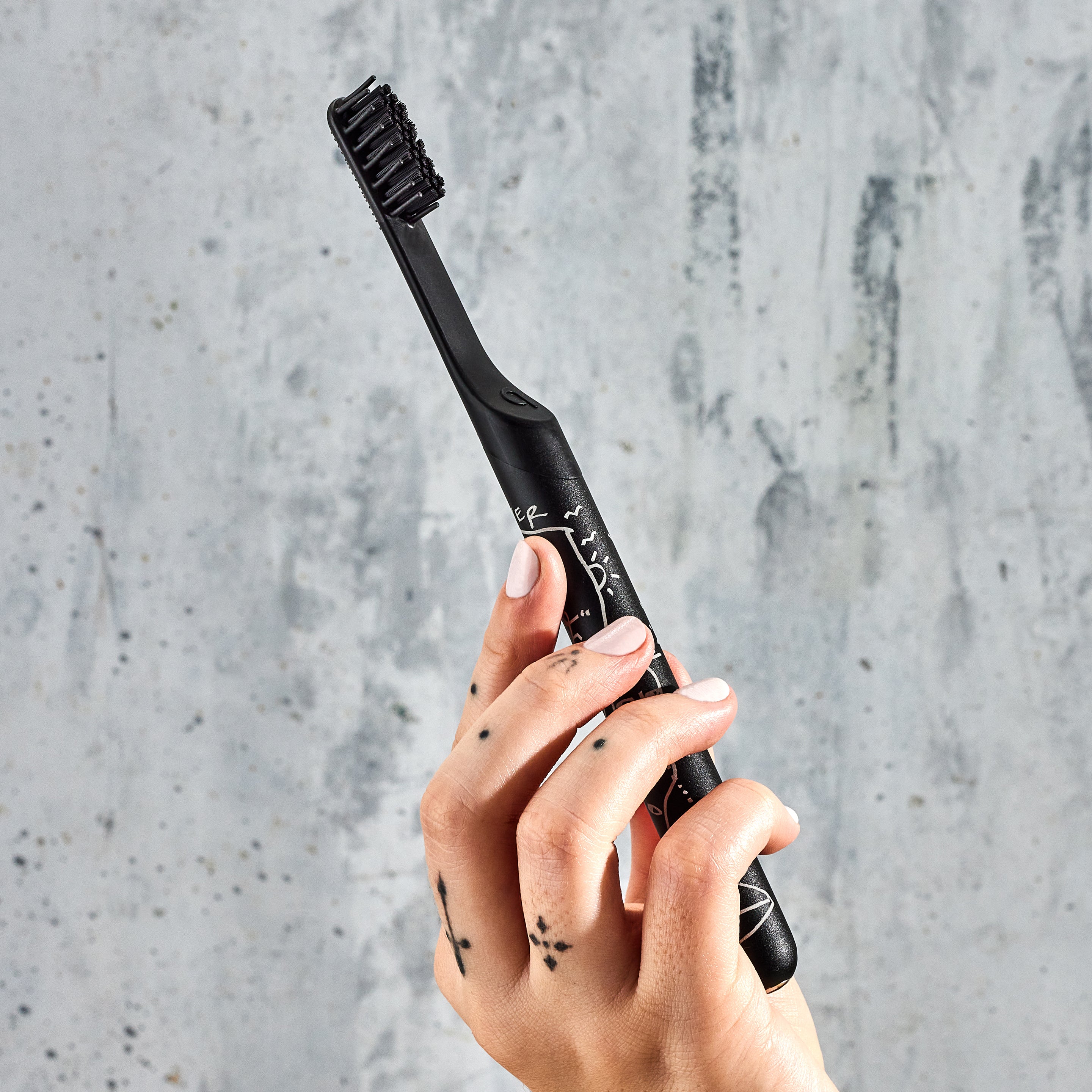 A hand holding a smart rechargeable sonic toothbrush with a black handle and a geometric pattern.