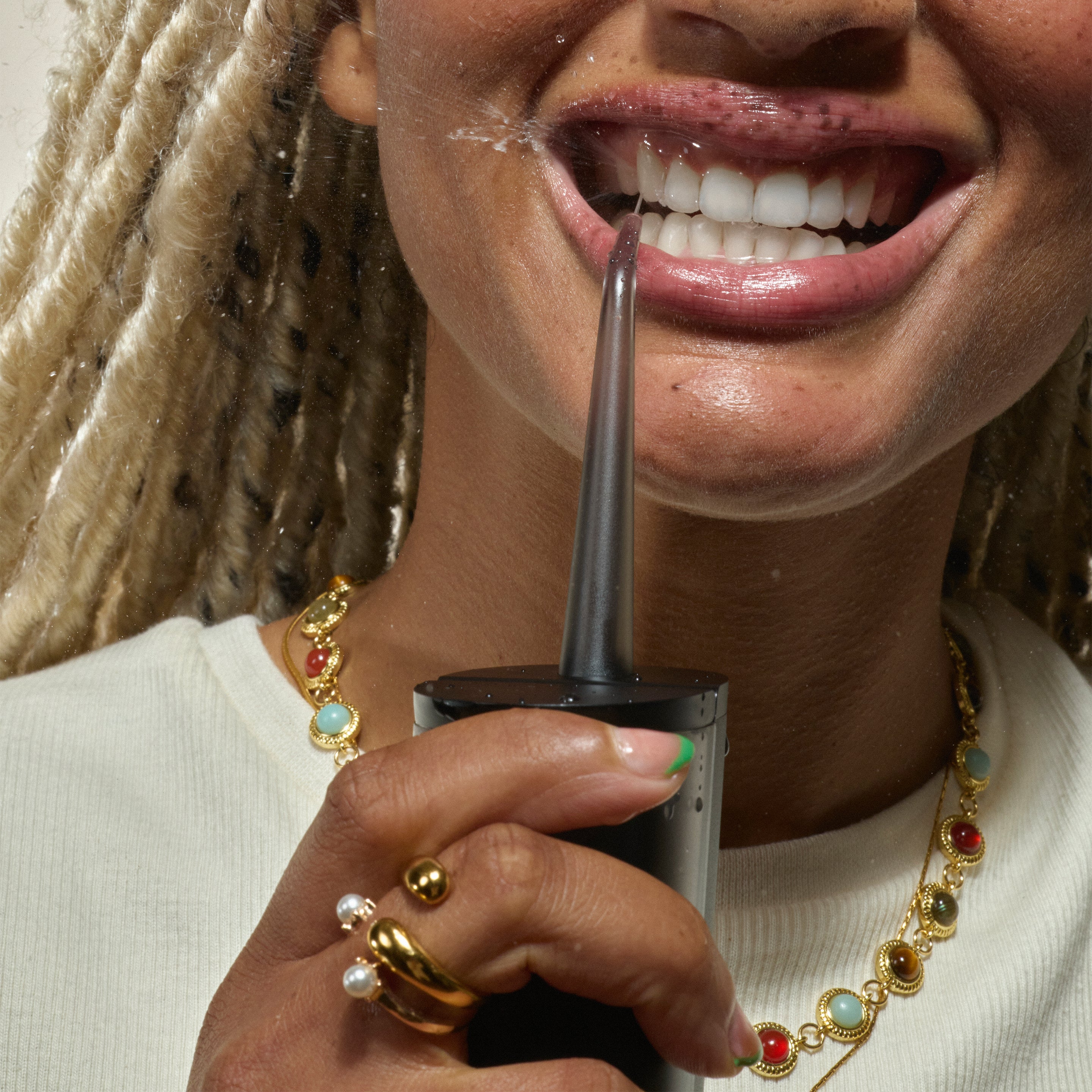 Person using a quip Water Flosser, aiming the water stream between their teeth.