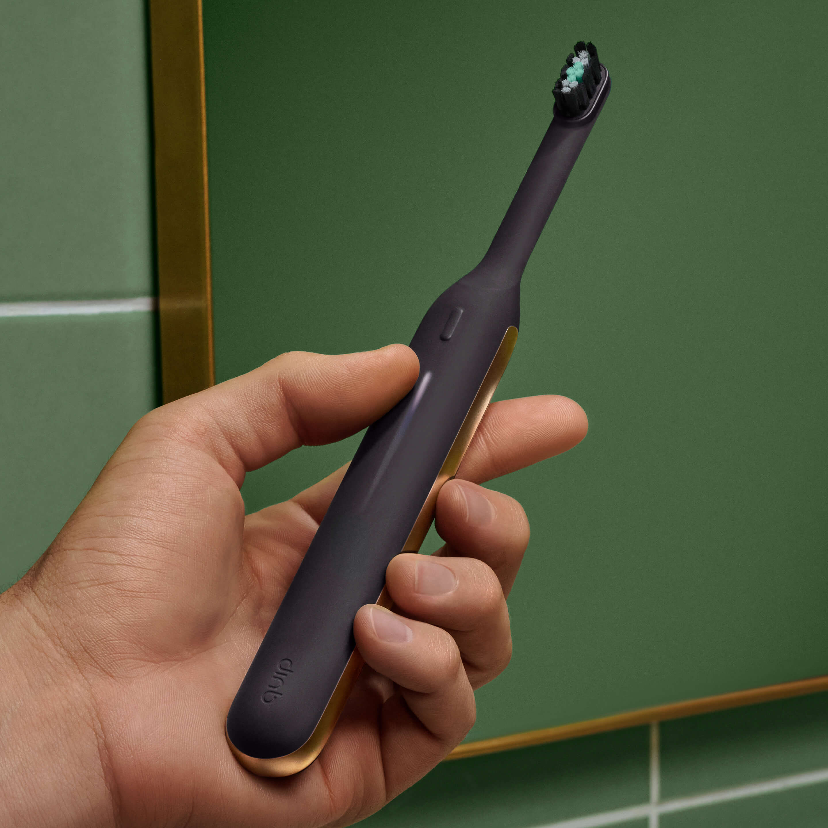 Hand holding the Ultra™ Next Generation Smart Sonic Electric Toothbrush in Eclipse color, showing its sleek matte black finish with gold metallic accents near the base.