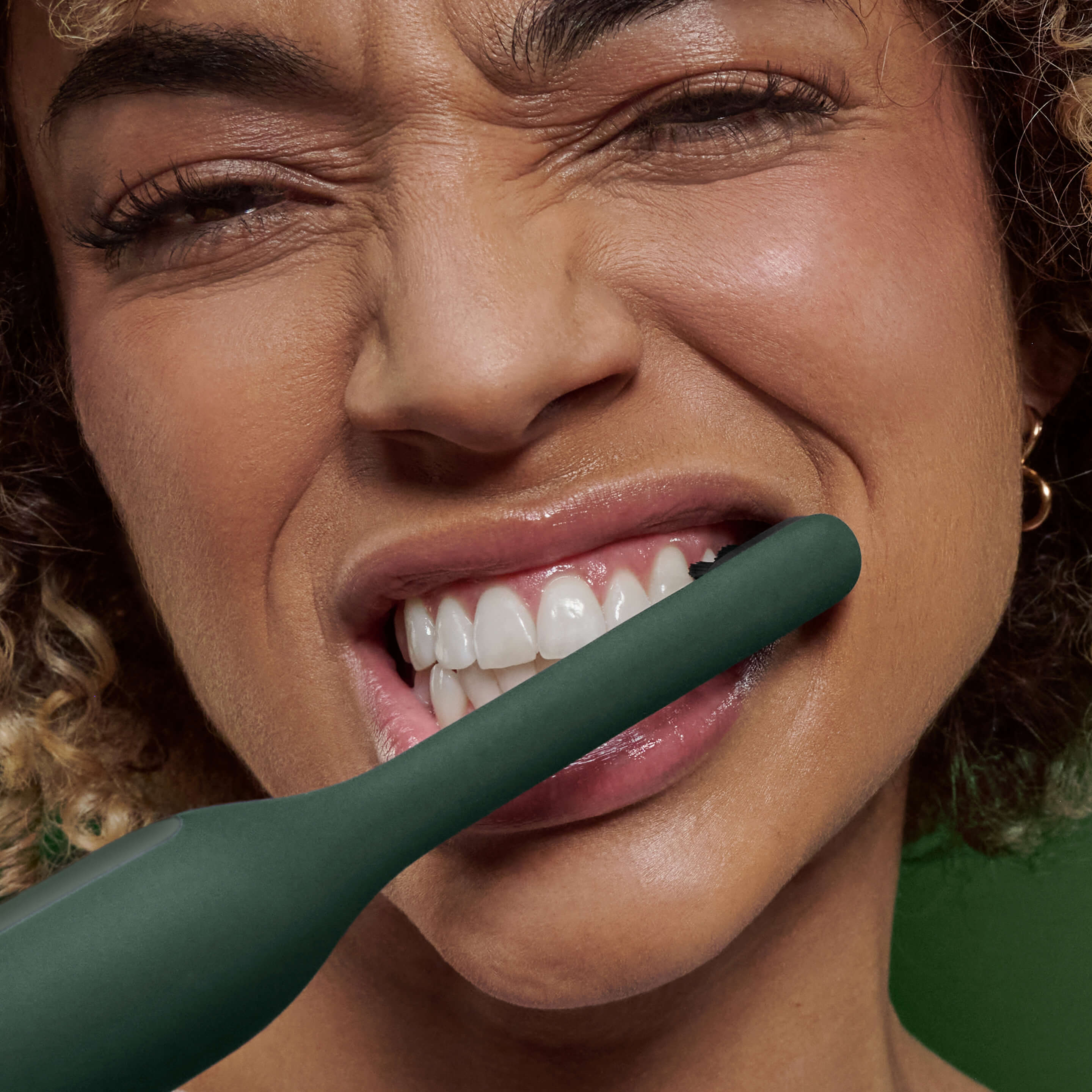 Person brushing their teeth with the Ultra™ Next Generation Smart Sonic Electric Toothbrush in Moss color, showing the brush in use close-up.