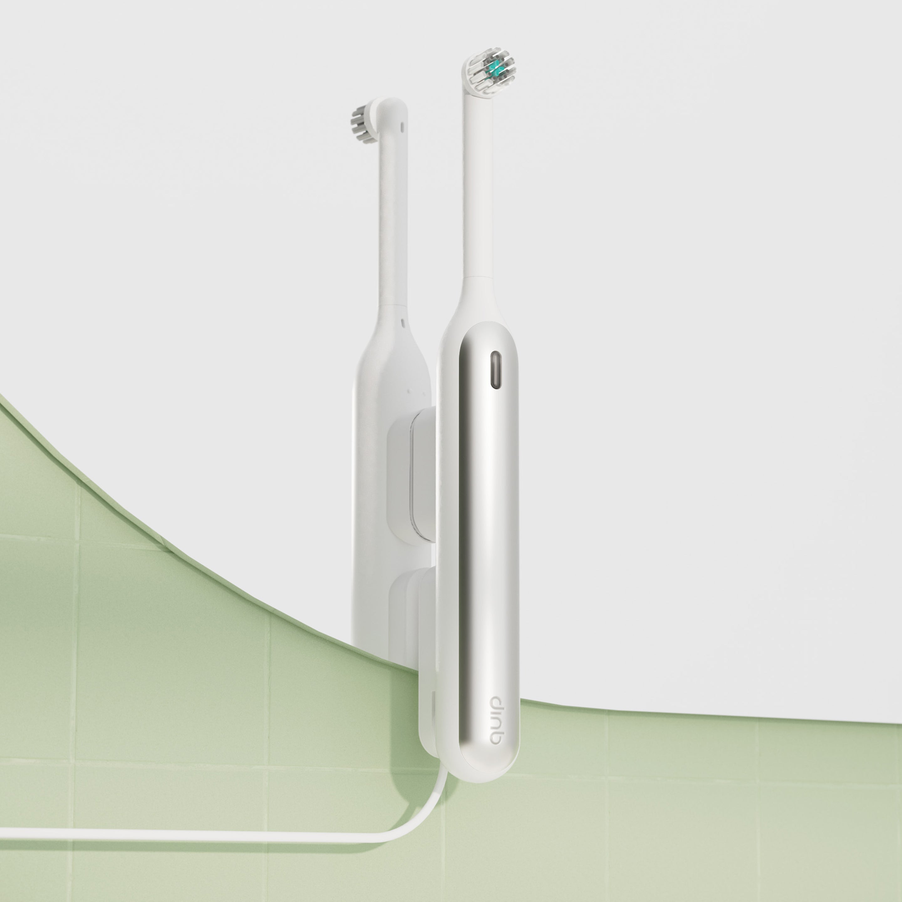 White Rev oscillating toothbrush mounted on a mirror with a matching white Rev mirror mount, with its white charging cable running down across a light green tiled wall.