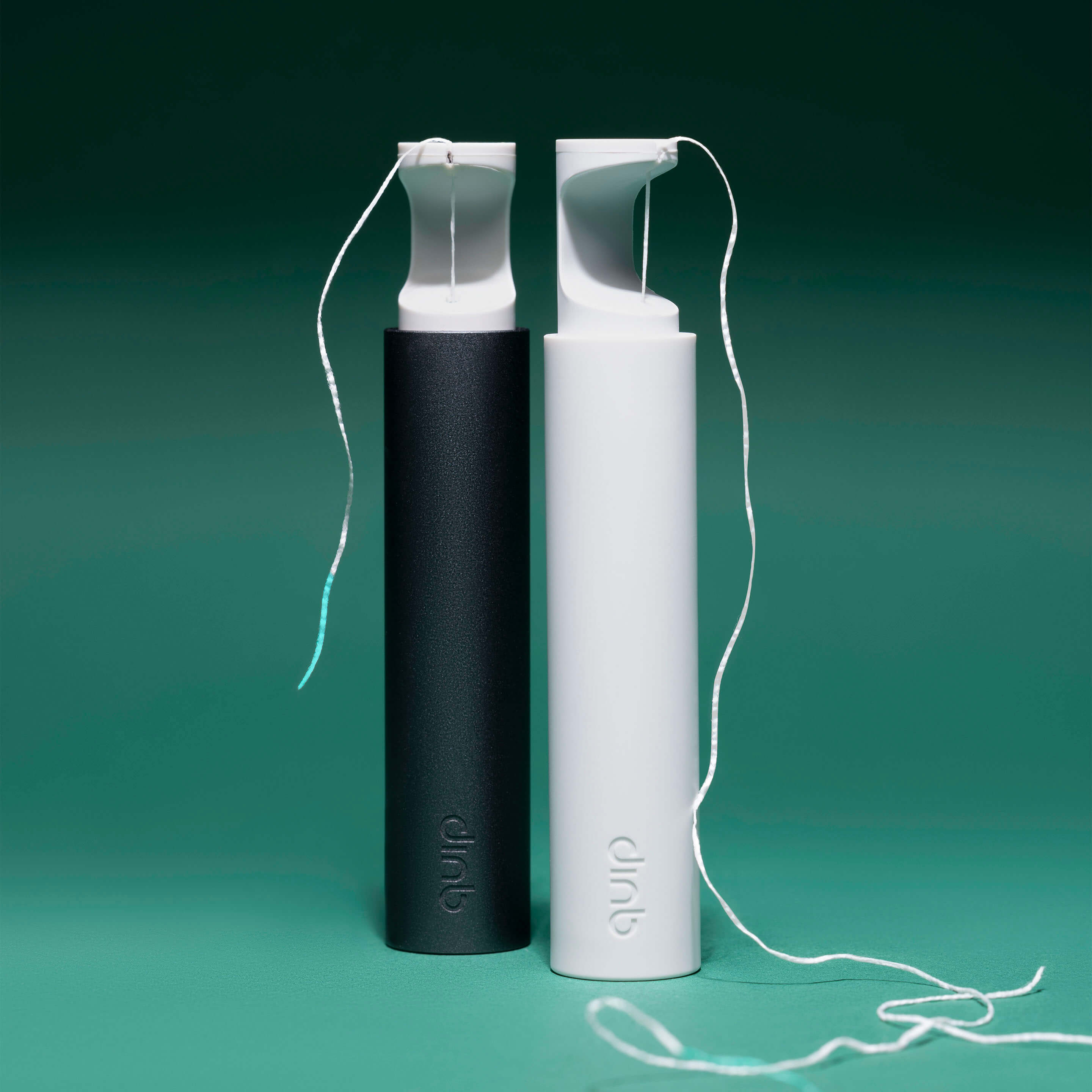 Two dental flossers, one black and one white, on a green background.