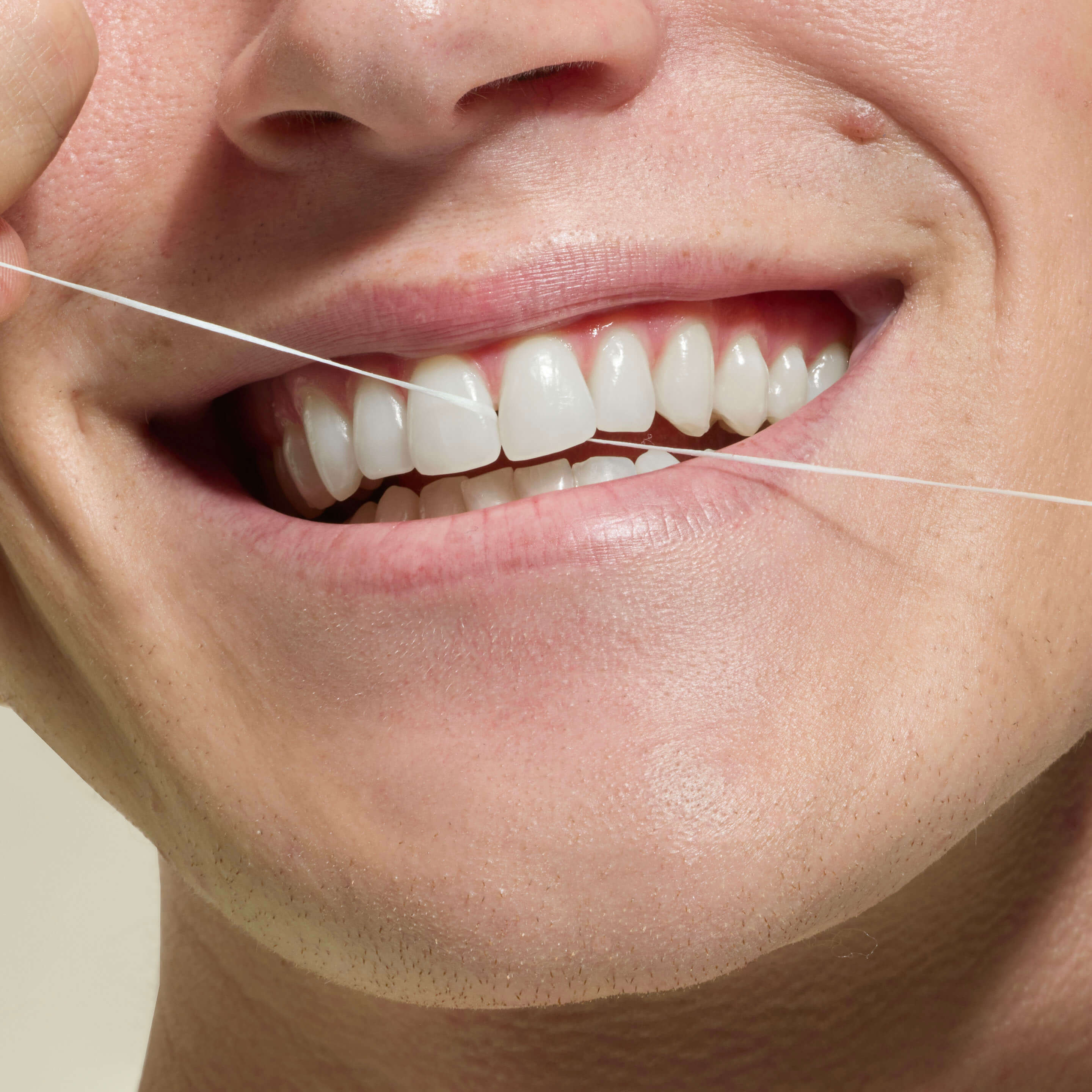 Close-up of a person using dental floss to clean their teeth.