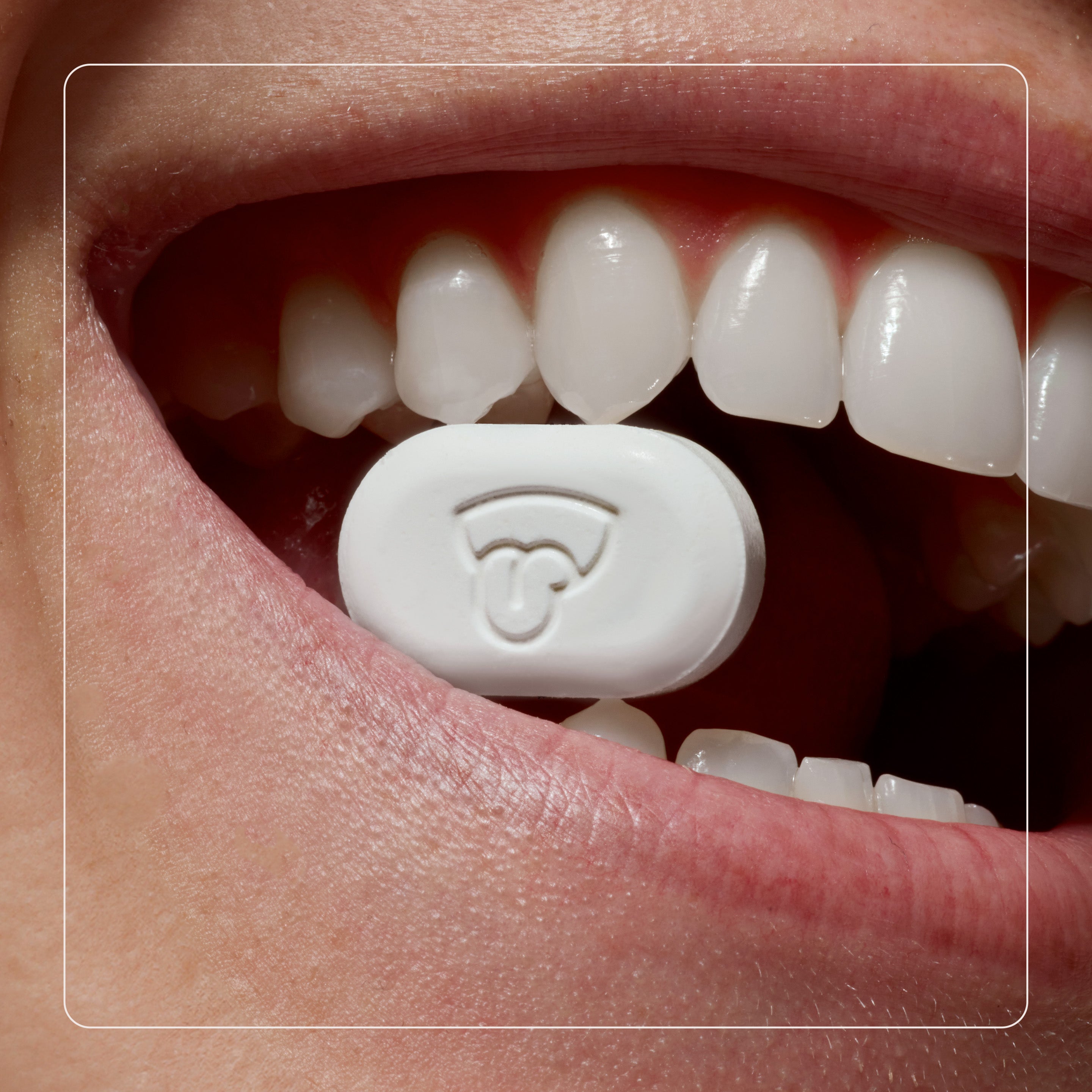 Close-up of a mouth with a white pill featuring a Wi-Fi symbol.