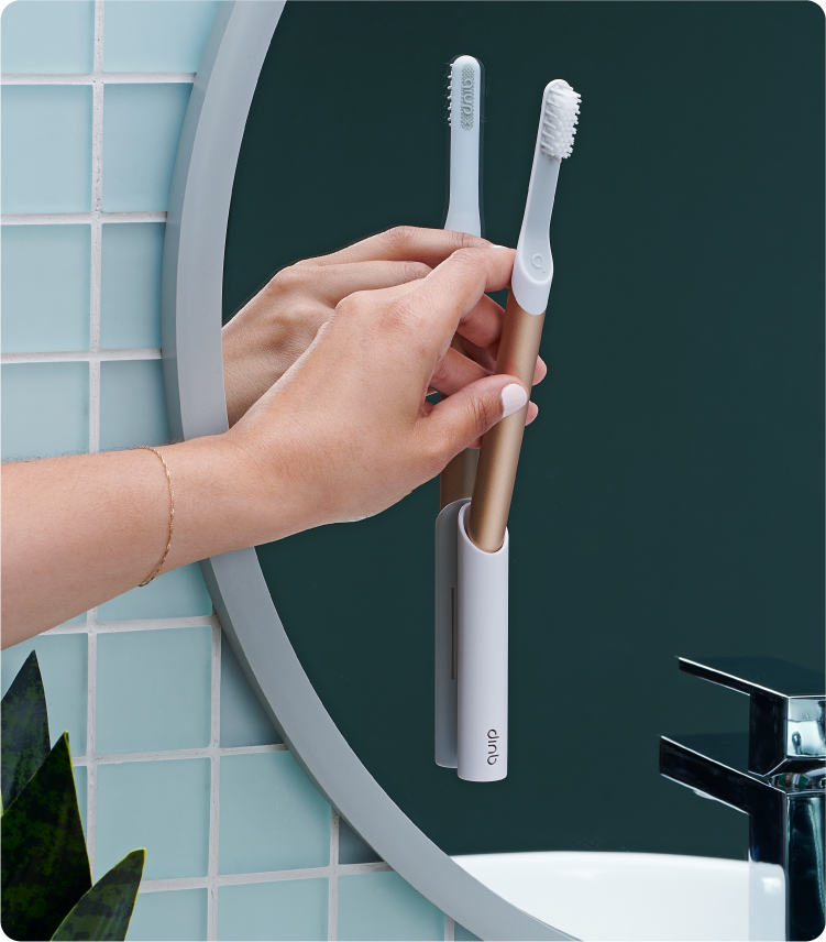 A model is inserting the quip Sonic Toothbrush into the quip mirror mount in the bathroom.