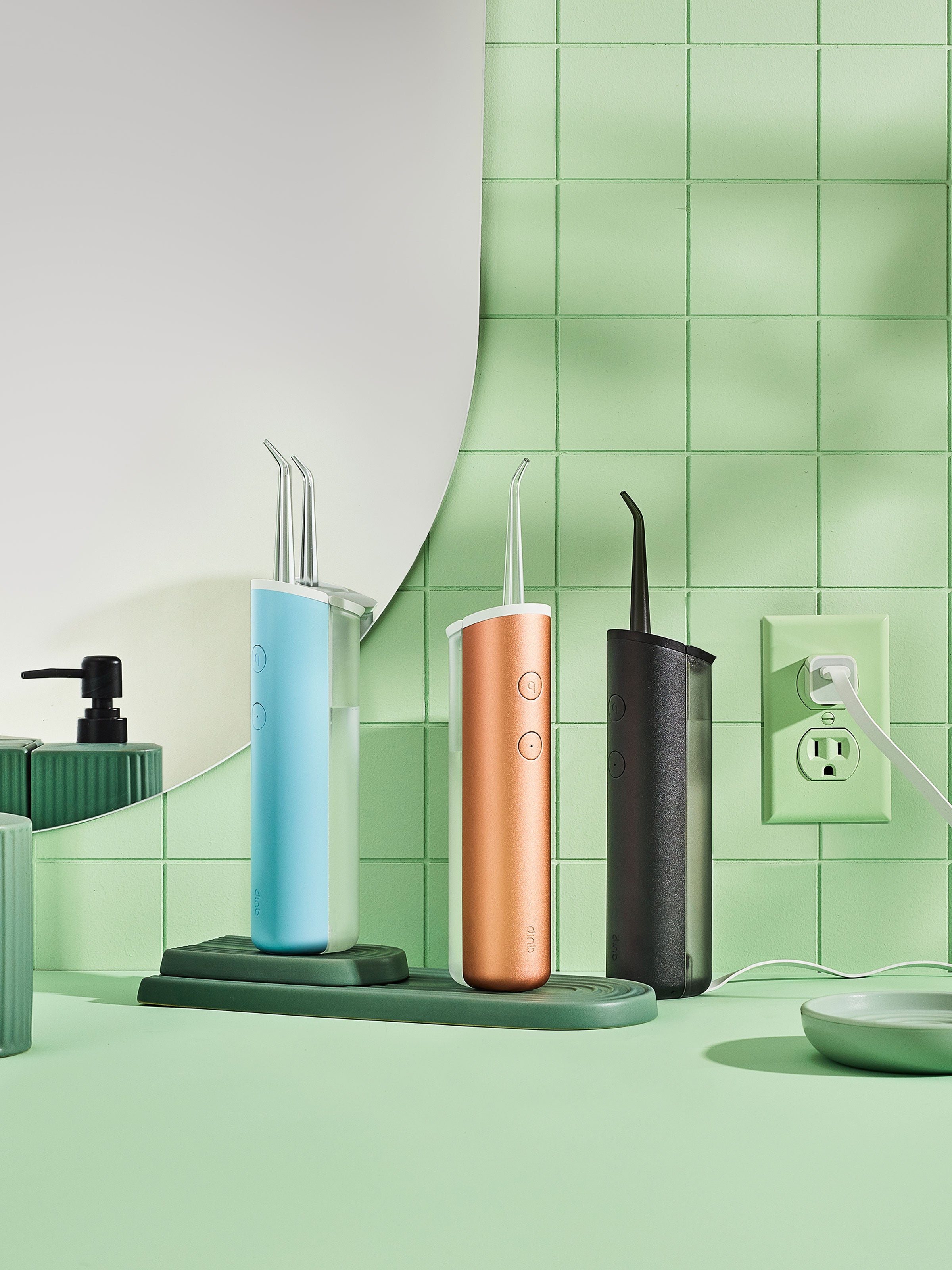 three quip Rechargeable Cordless Water Flossers sit on a bathroom sink