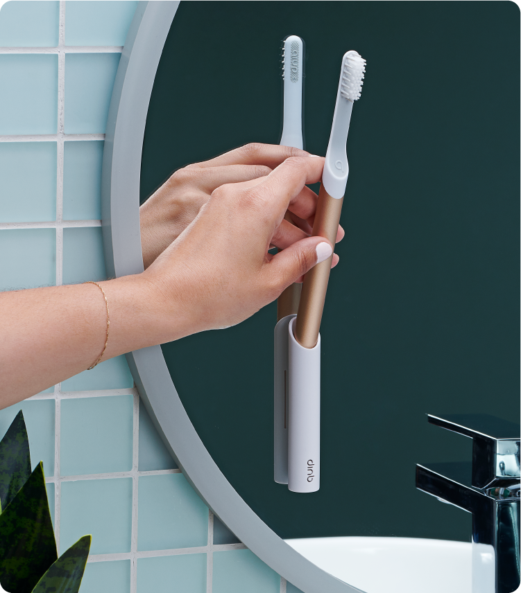 A model is inserting the quip Sonic Toothbrush into the quip mirror mount in the bathroom.