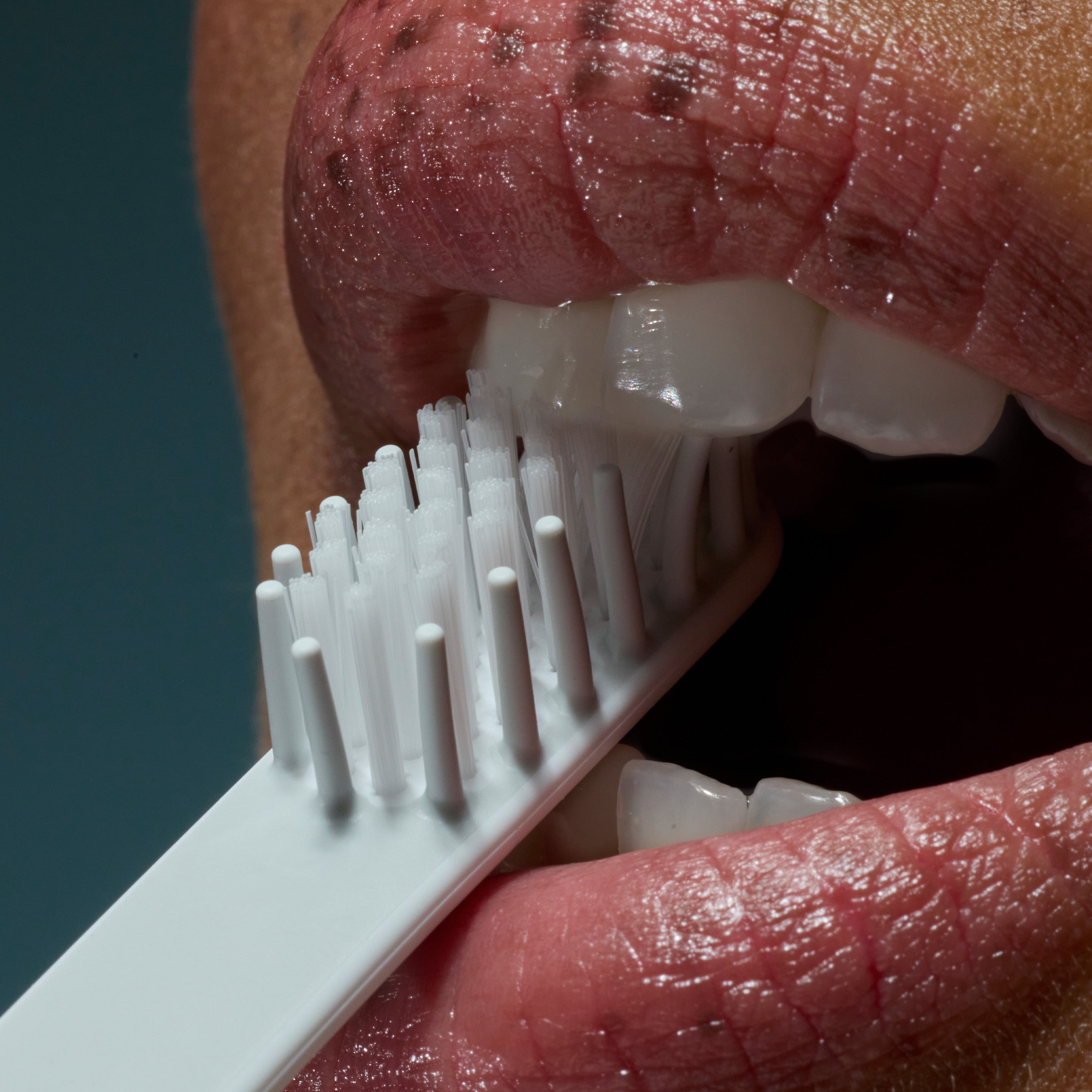Close-up of a toothbrush brushing teeth and lips.