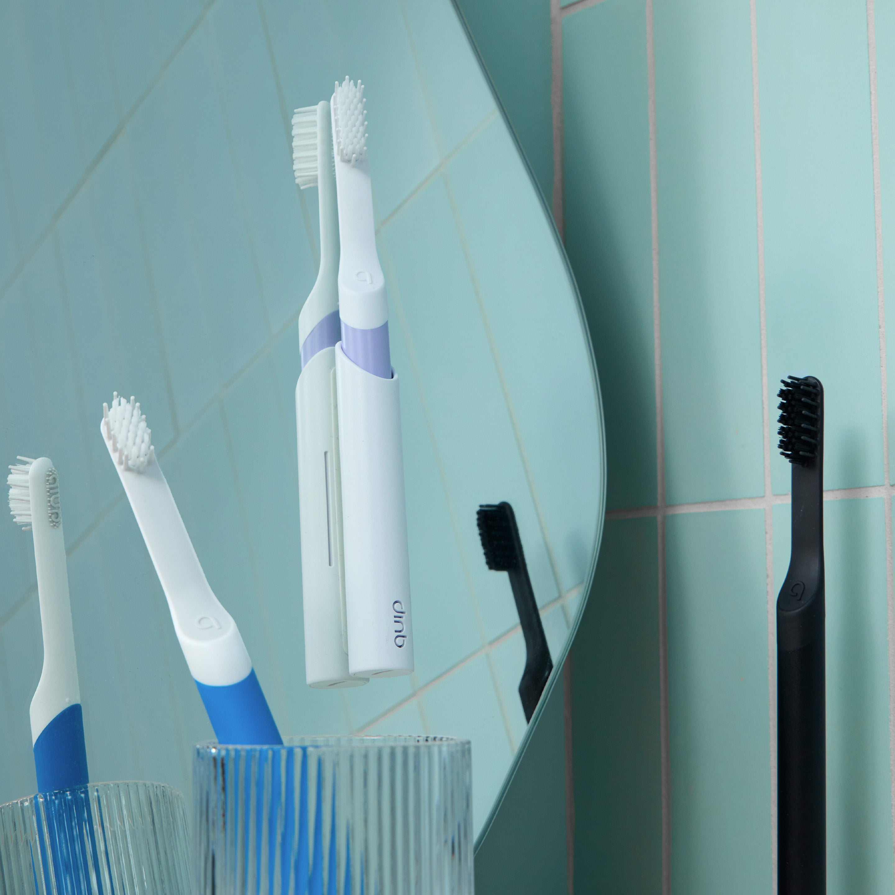 Hand holding a wet black toothbrush with water droplets on the handle and bristles.