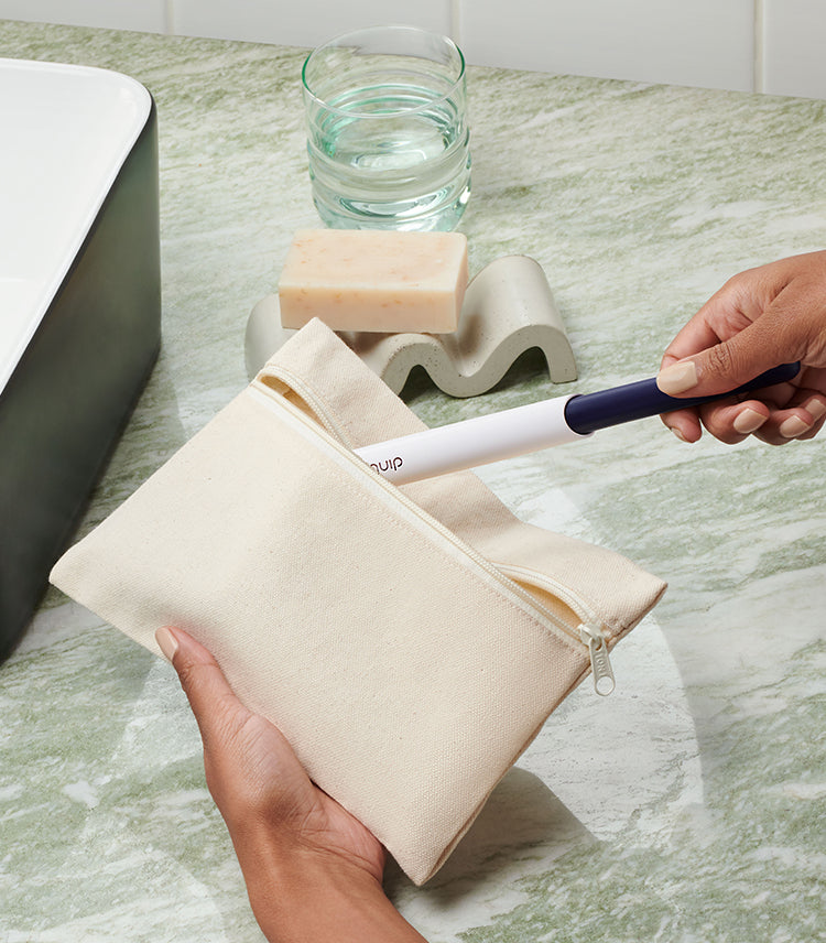 a model packing her quip sonic rechargeable toothbrush in a white pouch