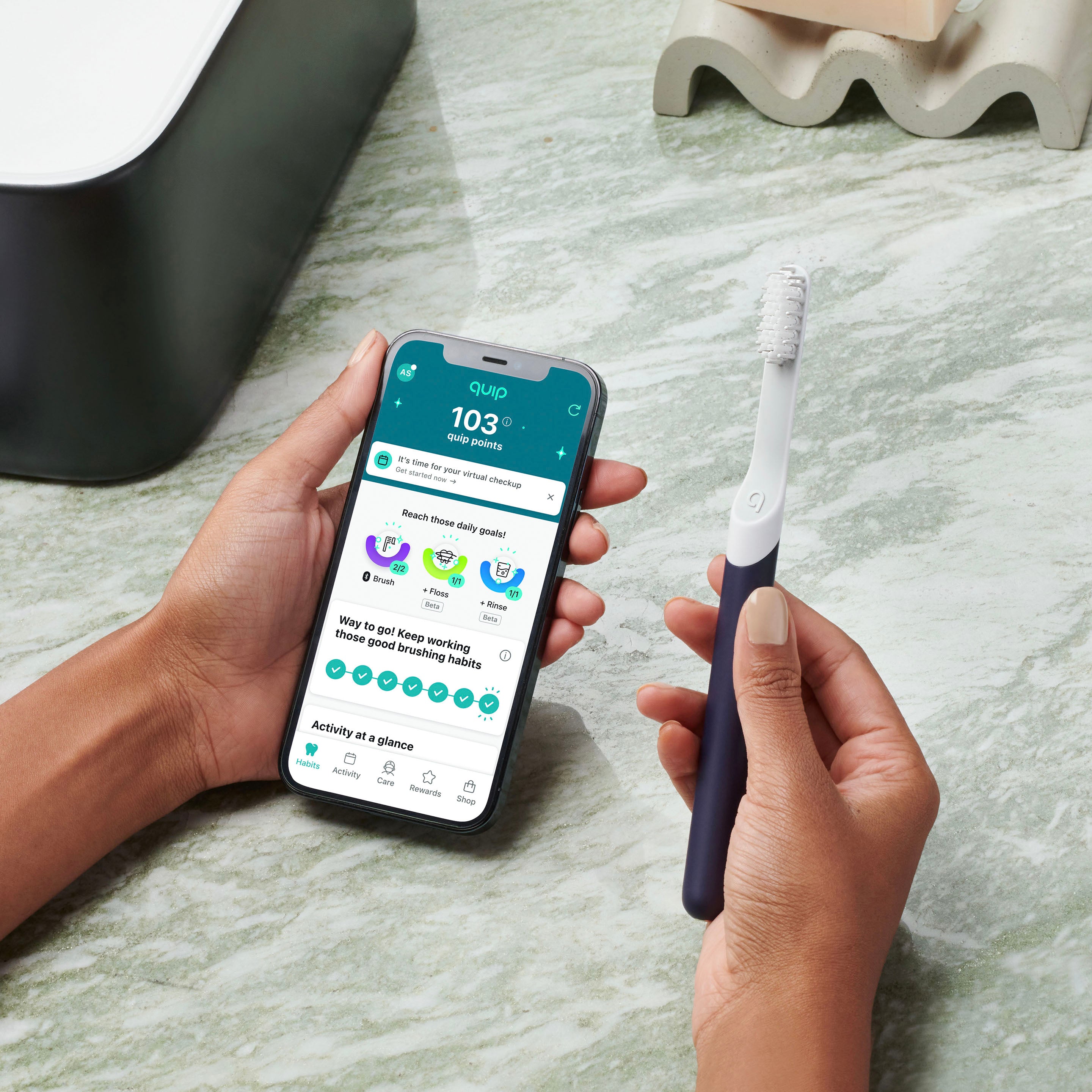Person holding a smartphone with a dental app and a toothbrush on a marble surface