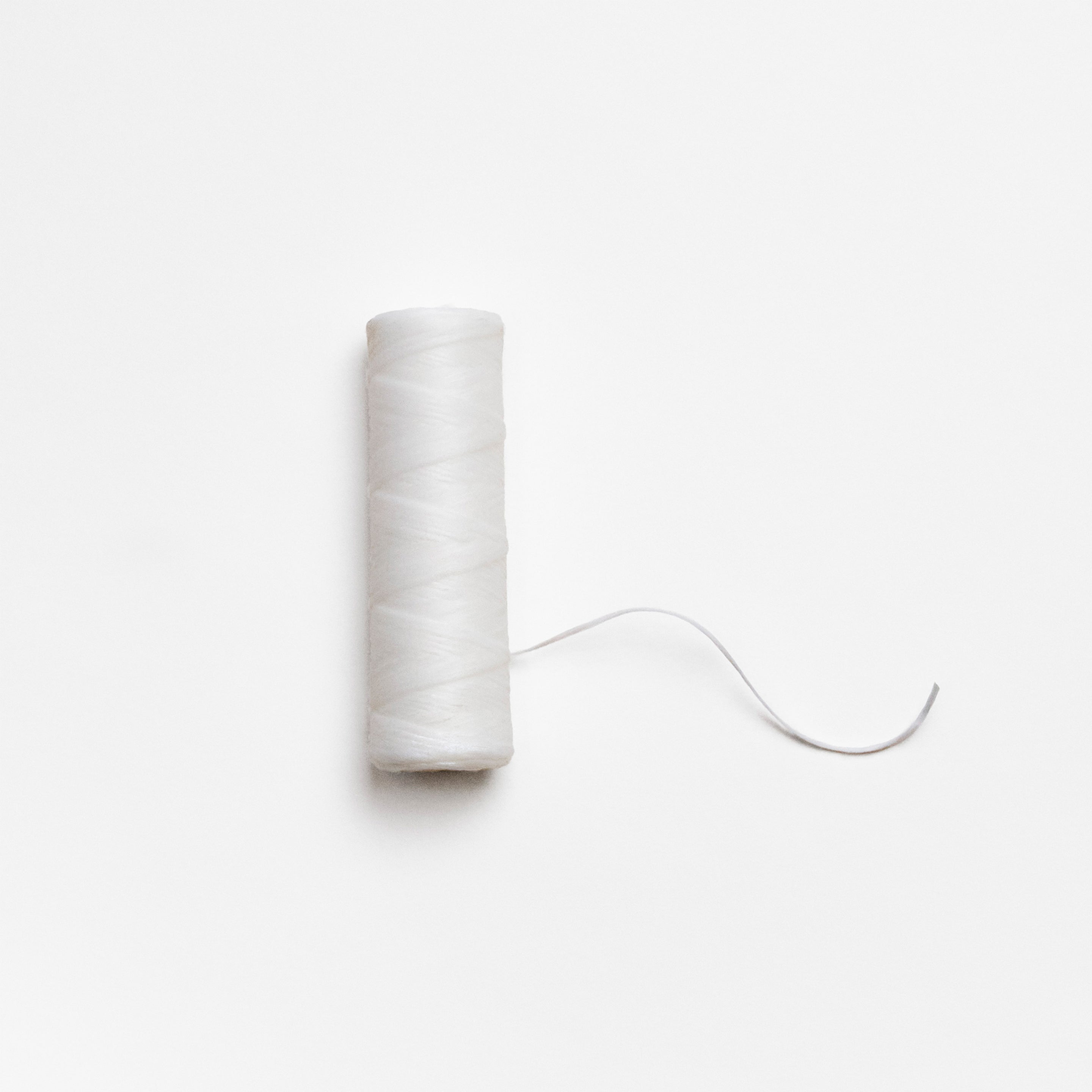 Spool of white thread on a light gray background