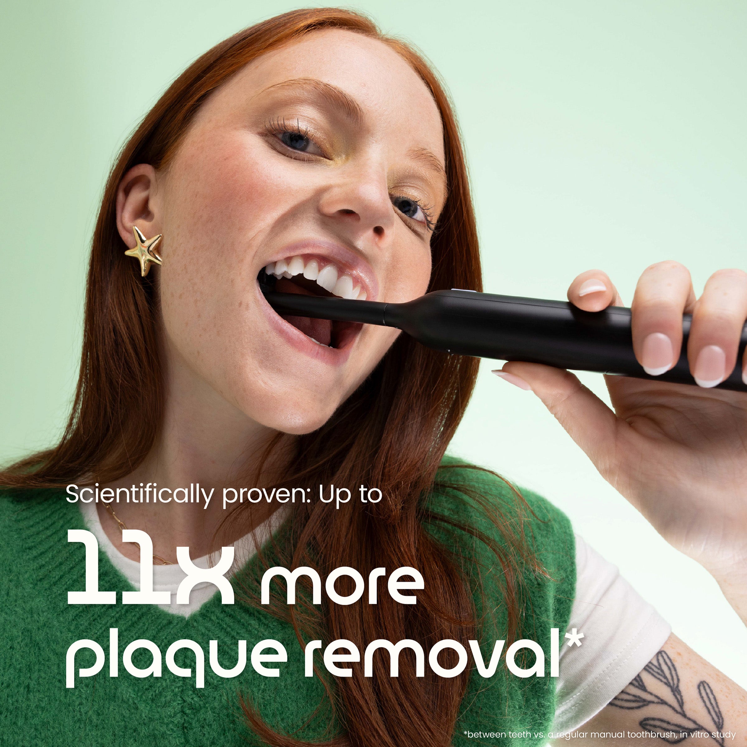 Woman brushing her teeth with a black toothbrush against a light green background, with text about plaque removal.