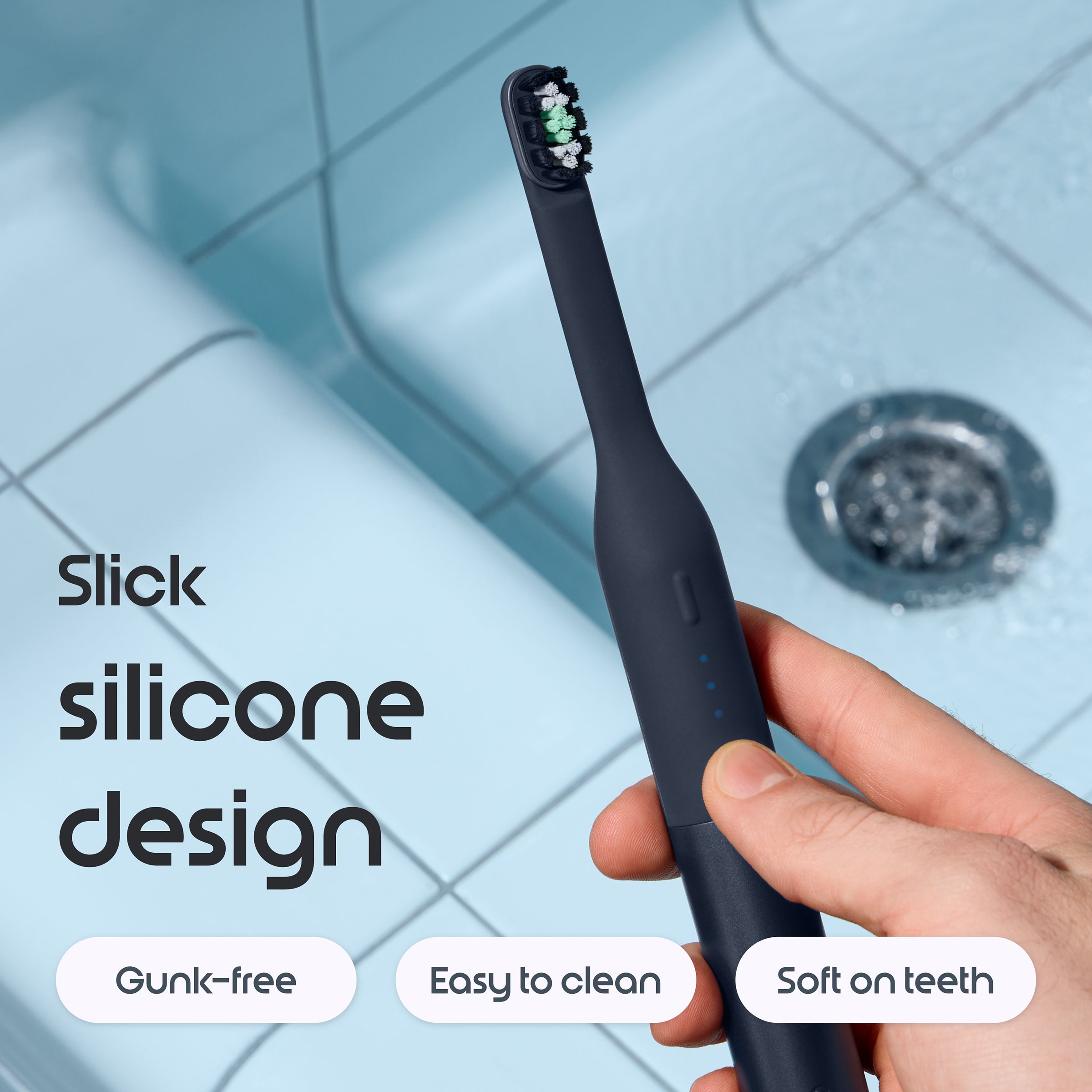 Black electric toothbrush held by a hand with text highlighting features on a tiled bathroom background.