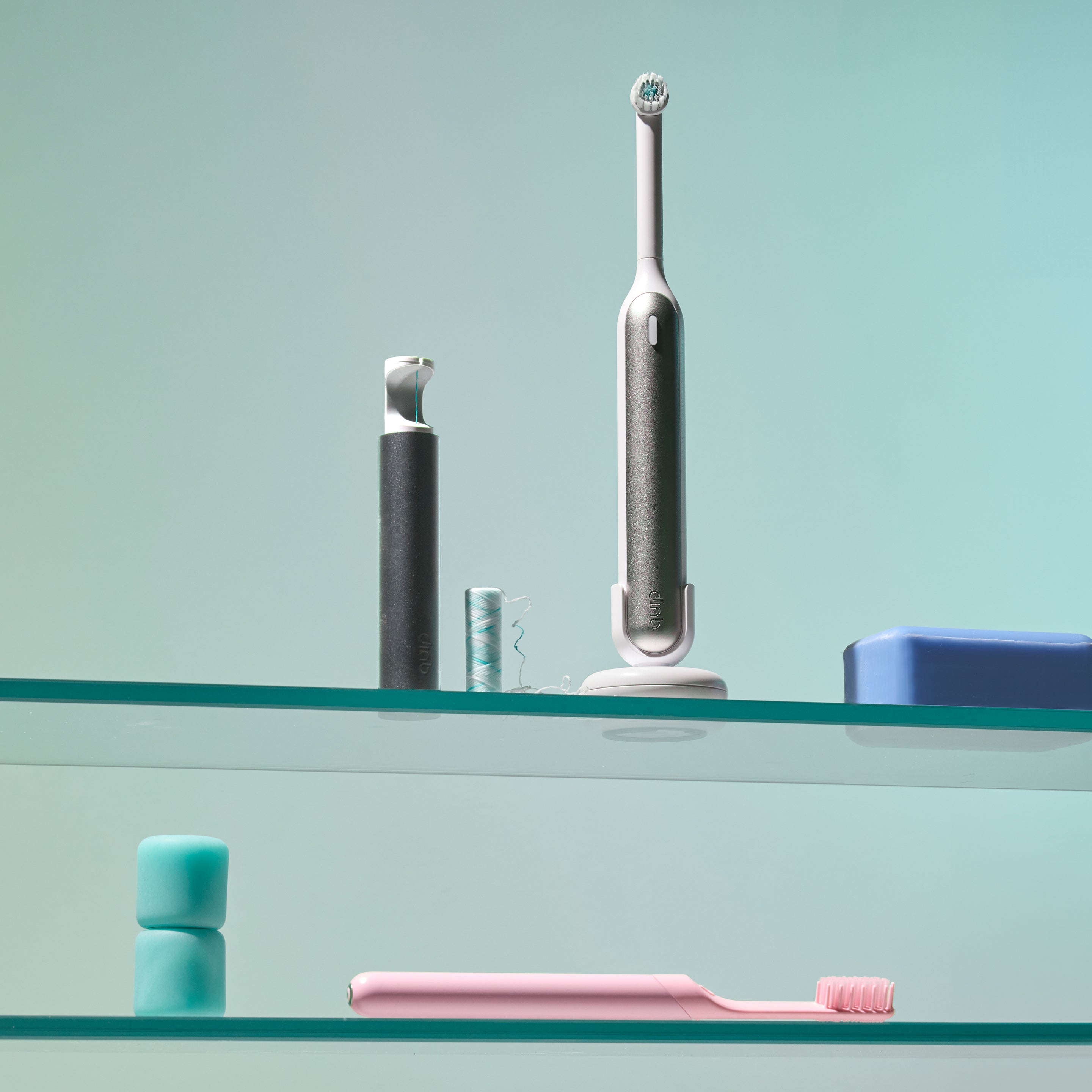quip Rev oscillating toothbrush sits on a shelf with a quip floss string