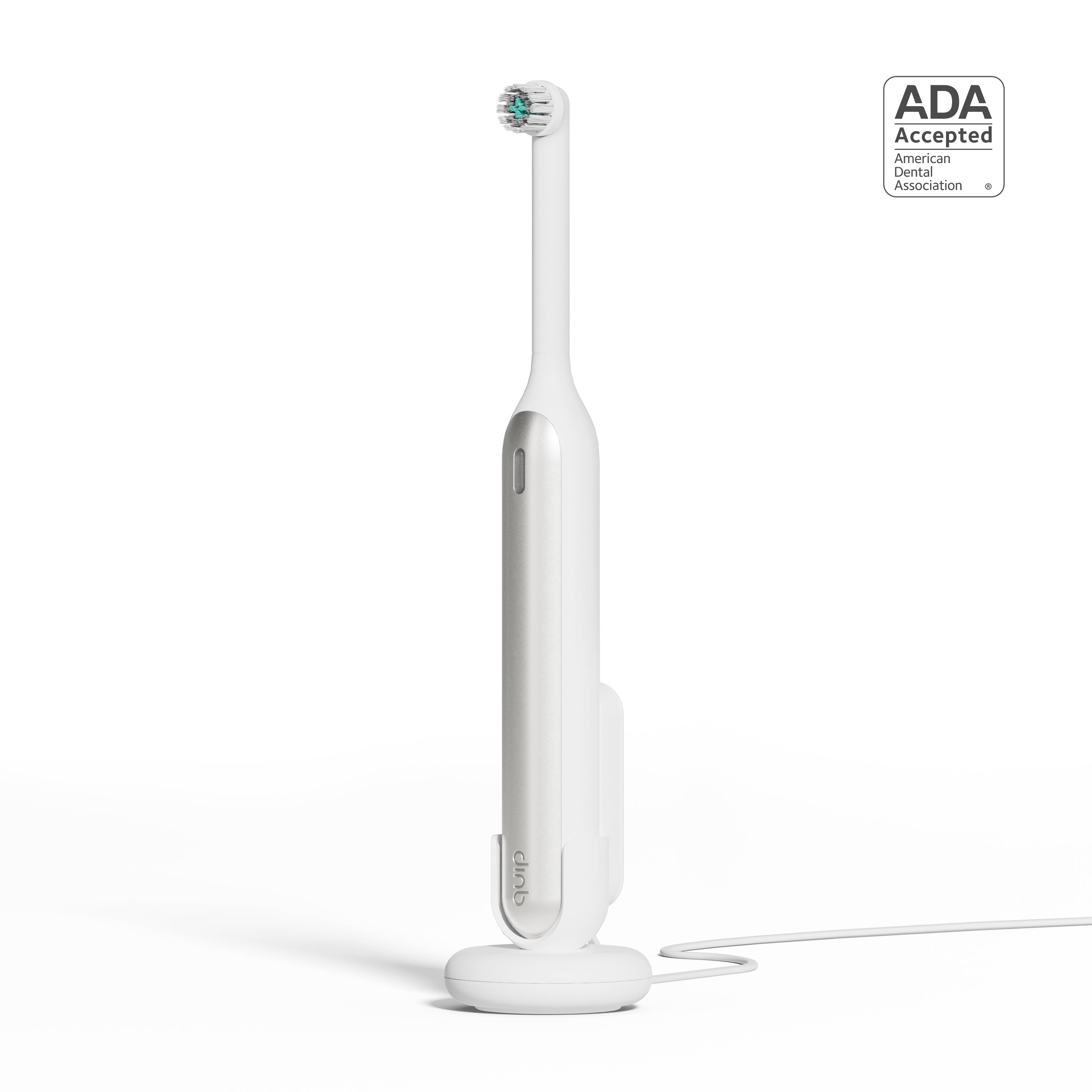 A white quip Rev Electric Toothbrush in the color Silver Cloud on its magnetic charging base, attached to a wall mount, with an ADA Accepted logo in the top right corner.