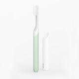 A sonic toothbrush with a green handle and white bristles, accompanied by a white travel cover.