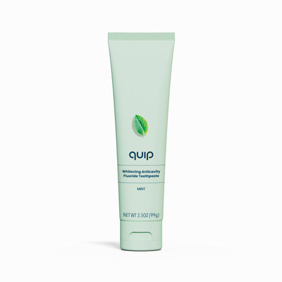 Green tube of quip toothpaste on a white background