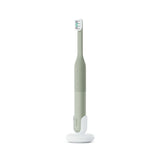 Green electric toothbrush with white base on a white background