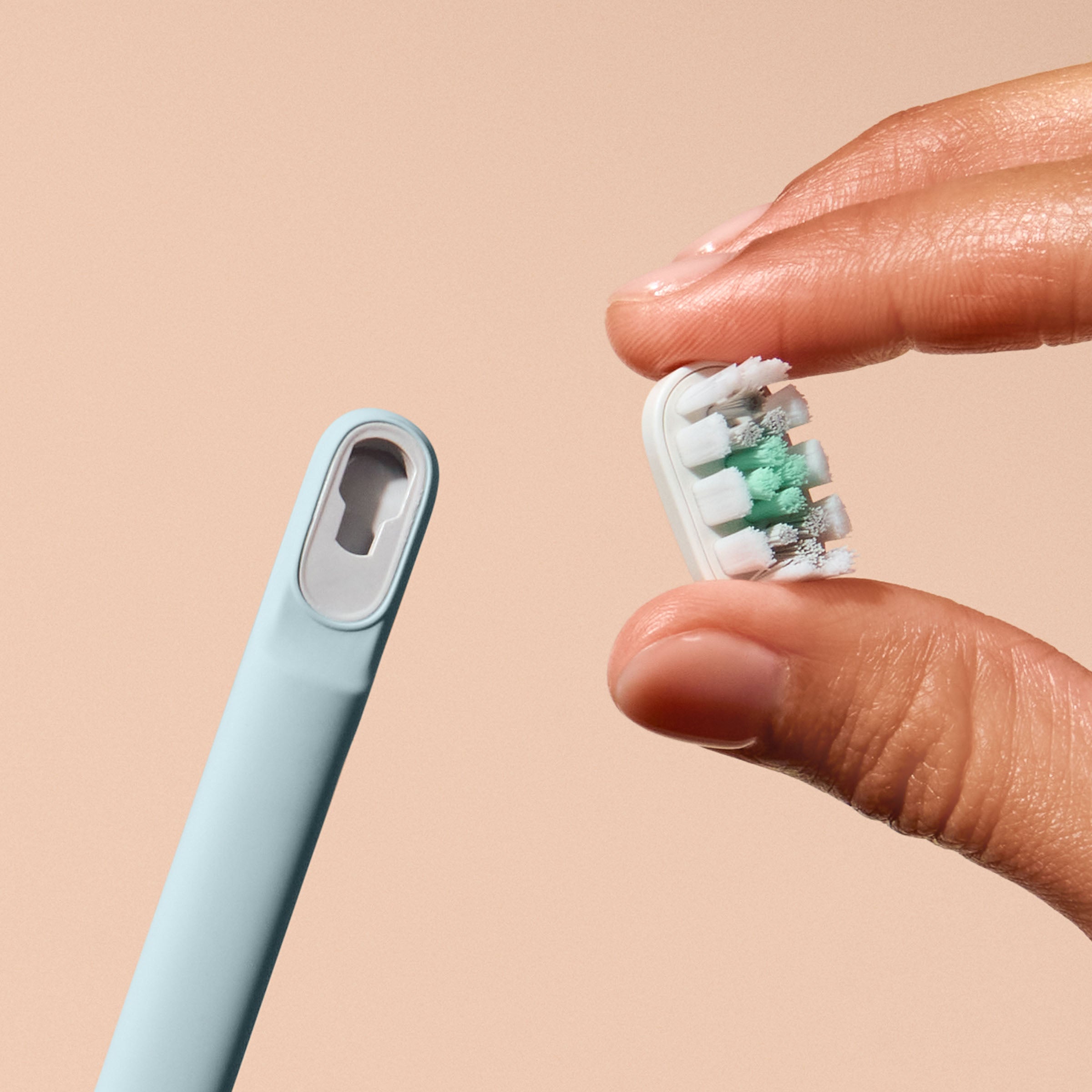 Hand holding a dental floss container with a beige background