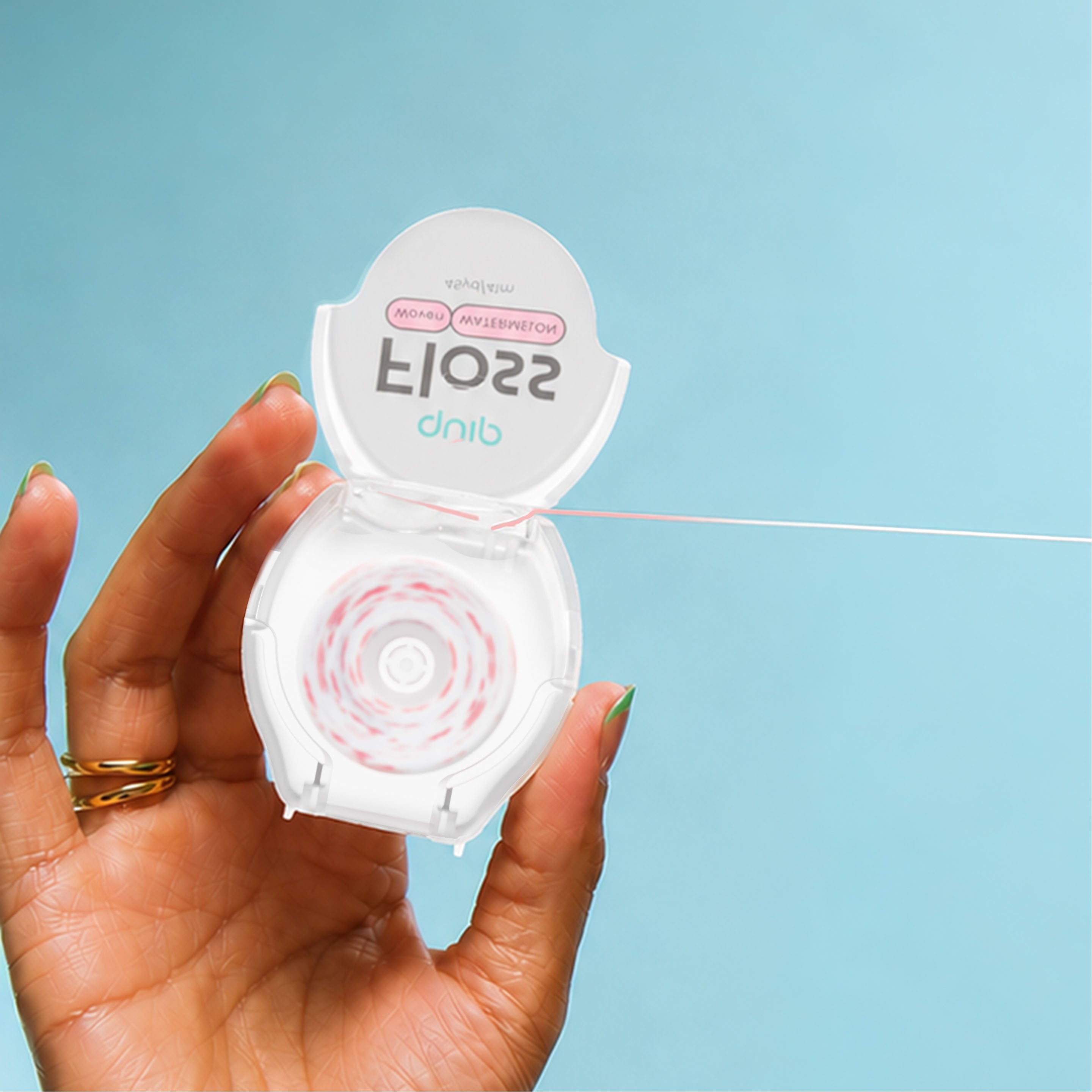 A hand holding an open white dental floss container against a light blue background, with floss visible spilling out from the right side.