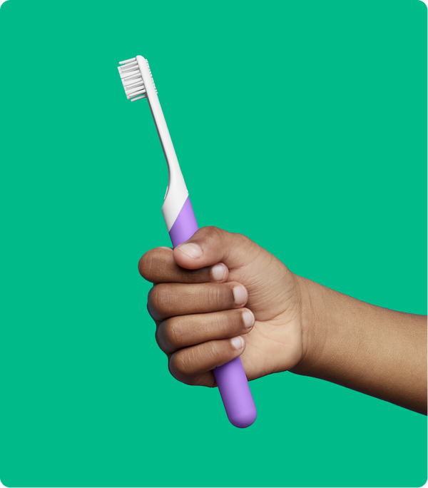A kid holding quip's kids purple sonic toothbrush