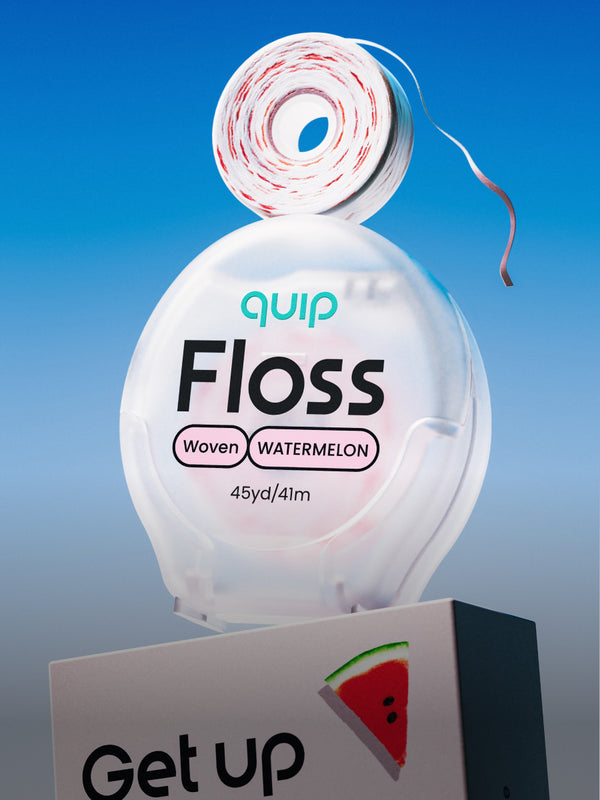 A roll of Quip Floss toothpaste floss is displayed above its clear plastic container, which is labeled 'Woven WATERMELON' and sits on a white display block with a watermelon graphic and the words 'Get up'. The background is a clean blue gradient.