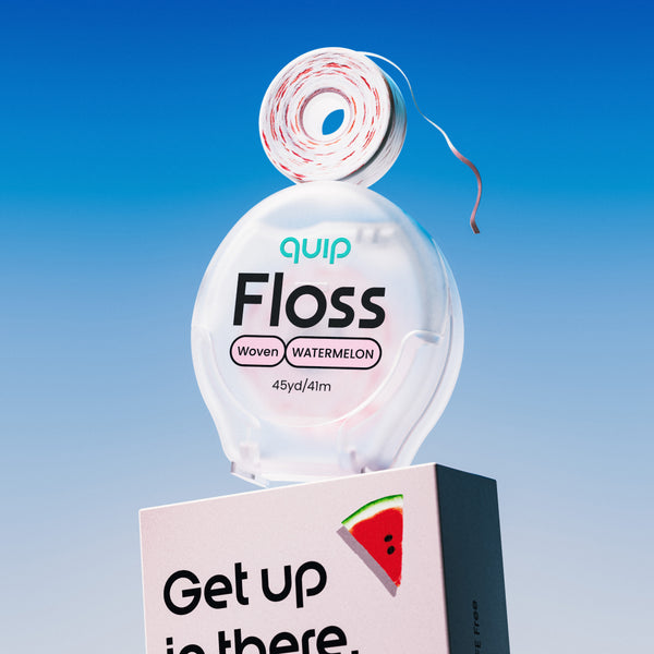 Quip Floss Woven Watermelon dental floss dispenser with a roll of floss on top, displayed on a white and black box against a blue gradient background.