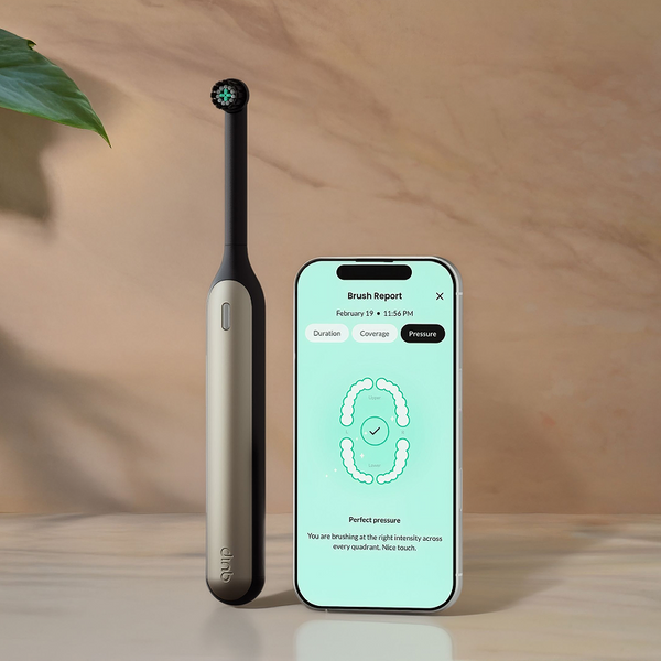 Smart toothbrush and smartphone displaying app on a wooden surface