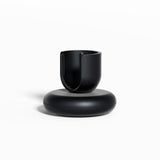 Black Rev Stand featuring a rounded base and an open, U-shaped holder for supporting a toothbrush, shown against a clean white background.