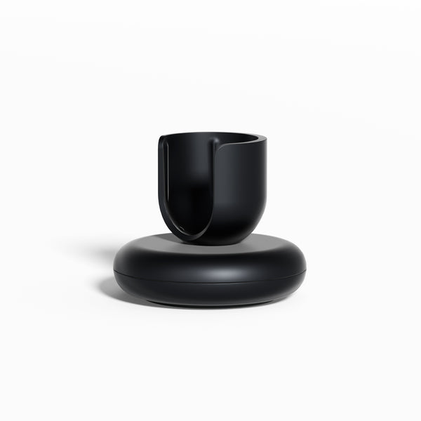 Black Rev Stand featuring a rounded base and an open, U-shaped holder for supporting a toothbrush, shown against a clean white background.