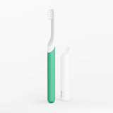 Green and white toothbrush on a light gray background